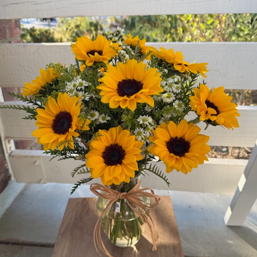 Sunflower bouquet in a clear glass vase with a ribbon bow