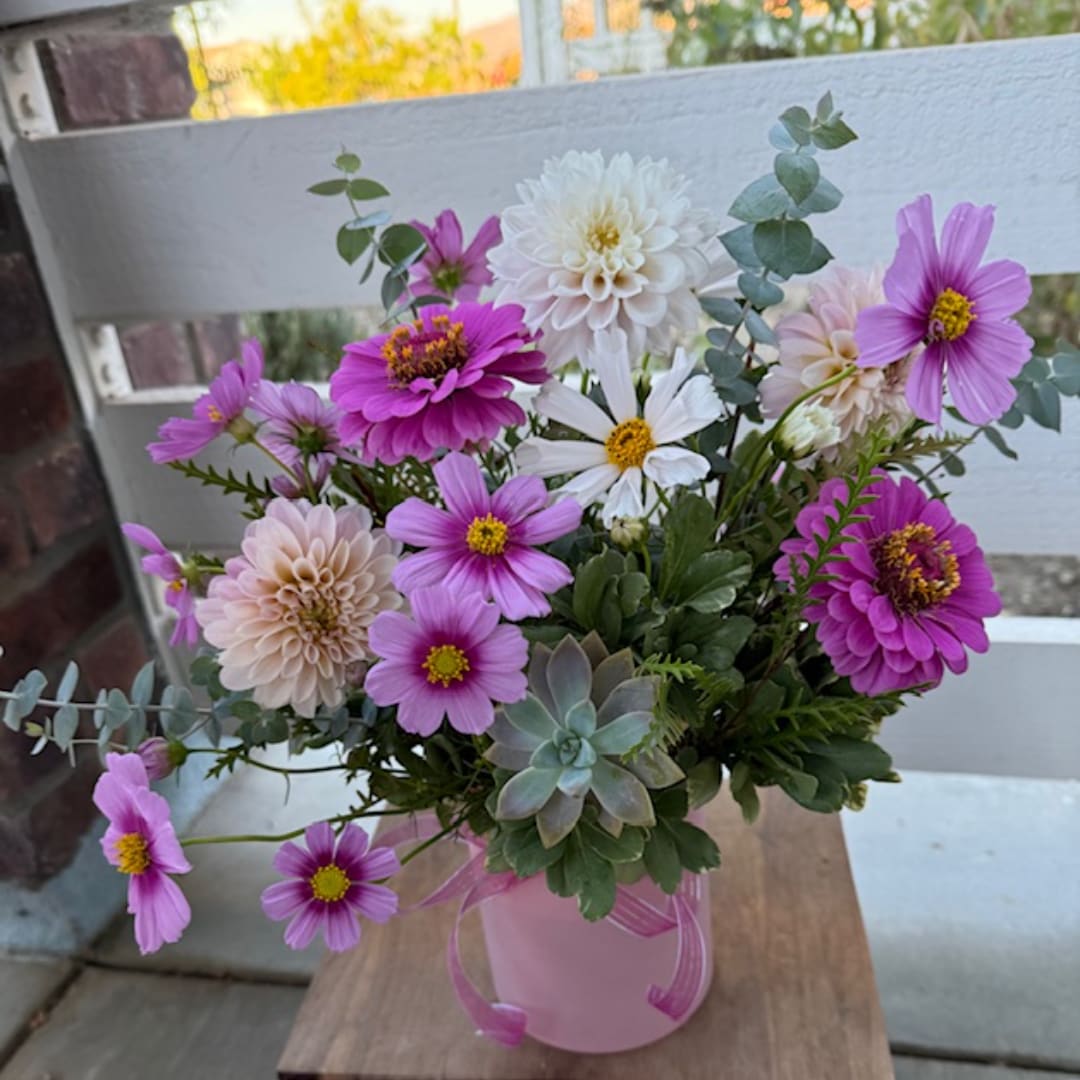 Pink and white flowers in a pink vase with succulents