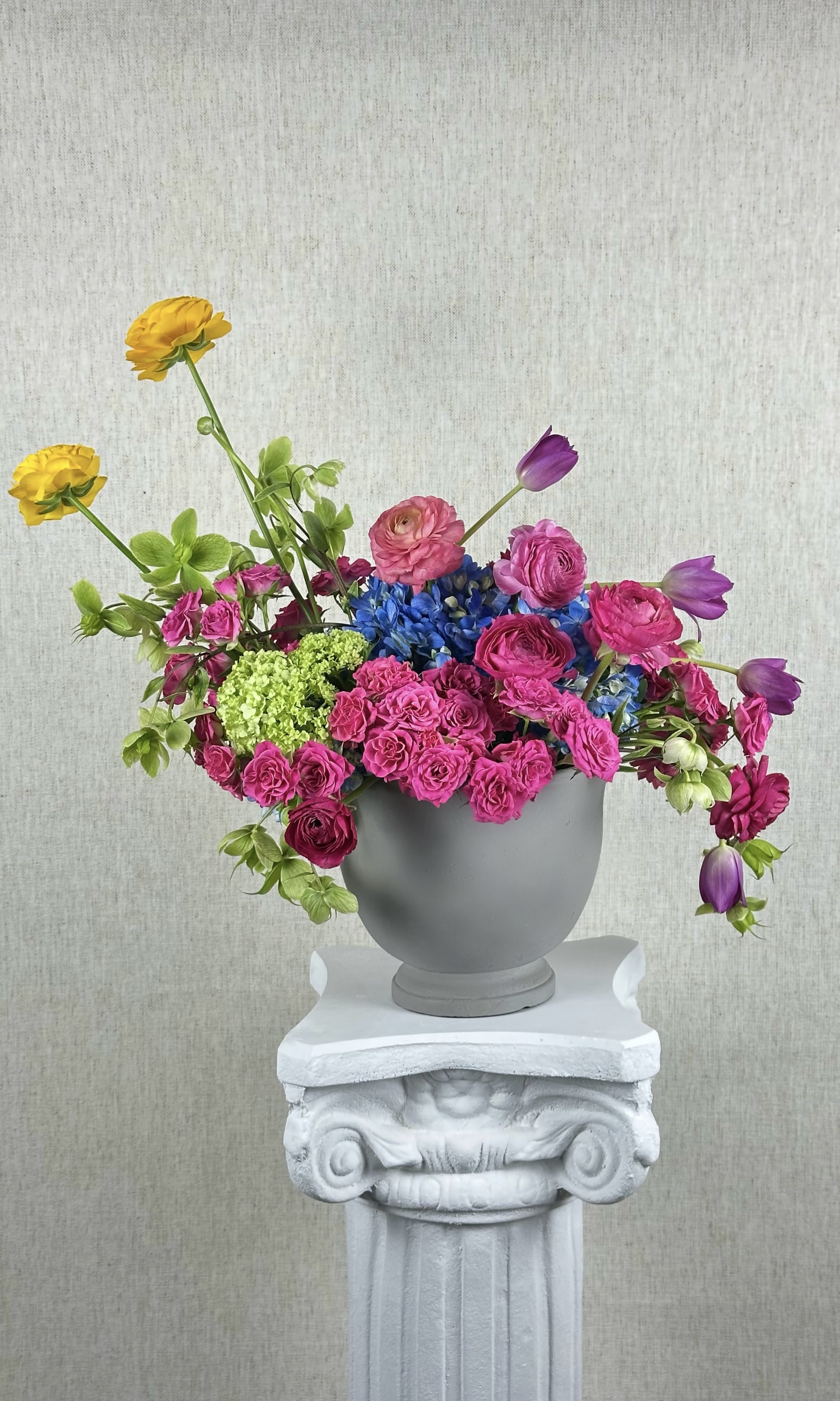 Colorful mixed flower arrangement in a gray urn vase