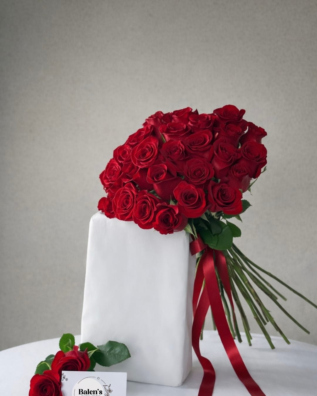 Bouquet of red roses tied with a red ribbon, with a matching rose boutonniere below
