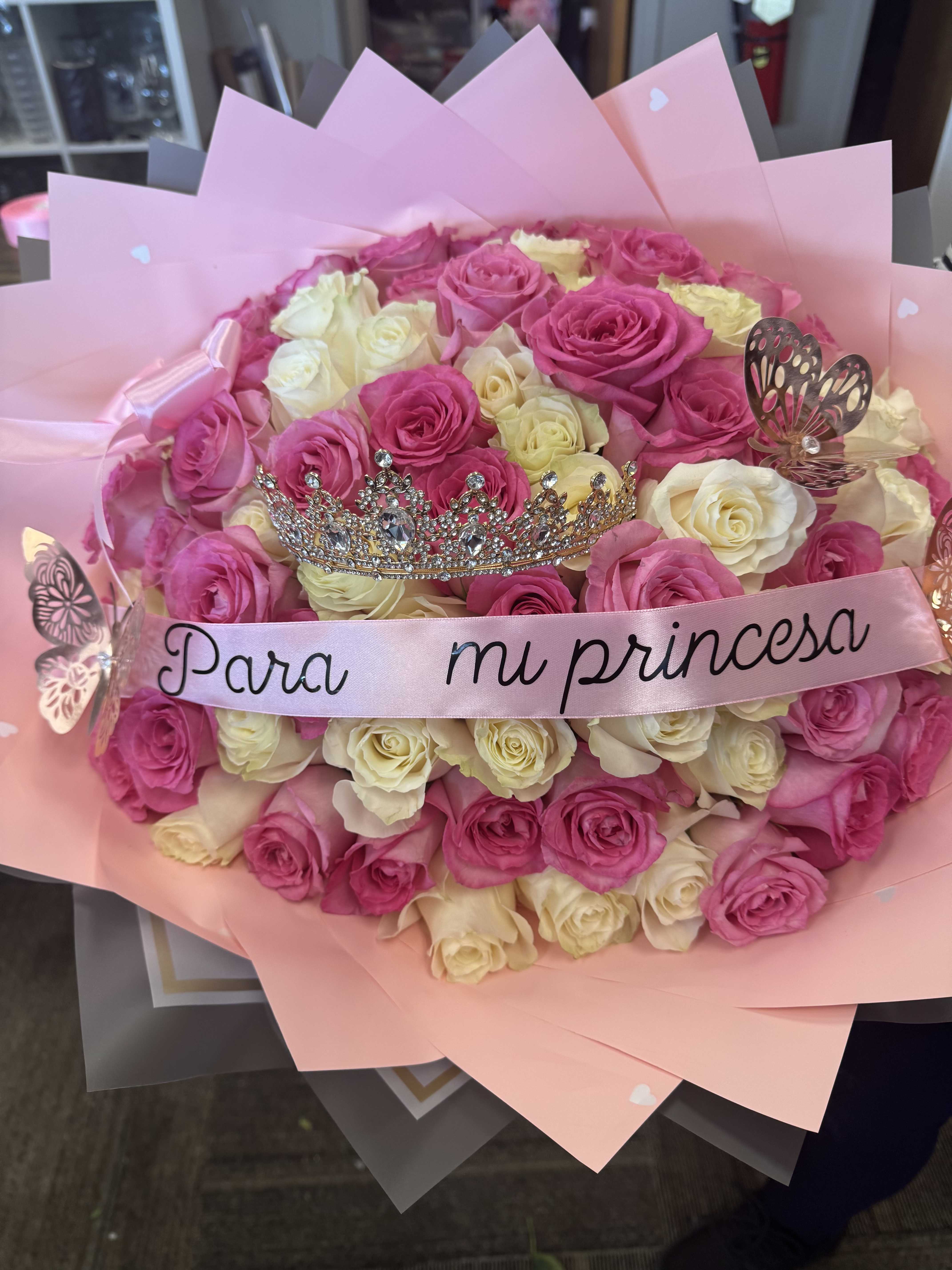 Pink and white rose bouquet with a tiara and ribbon reading "Para mi princesa"