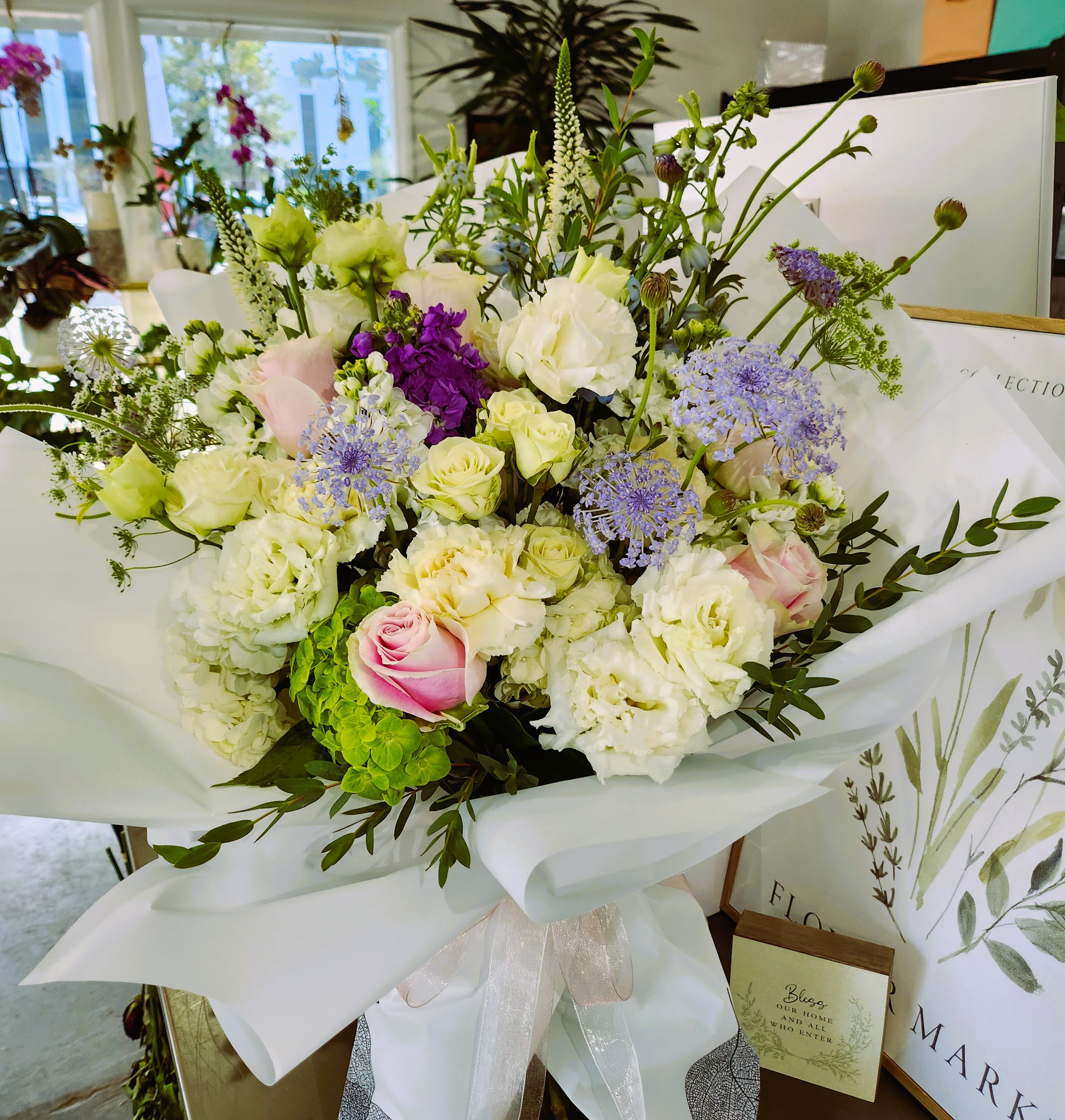 Bouquet of white, pink, and purple flowers wrapped in white paper