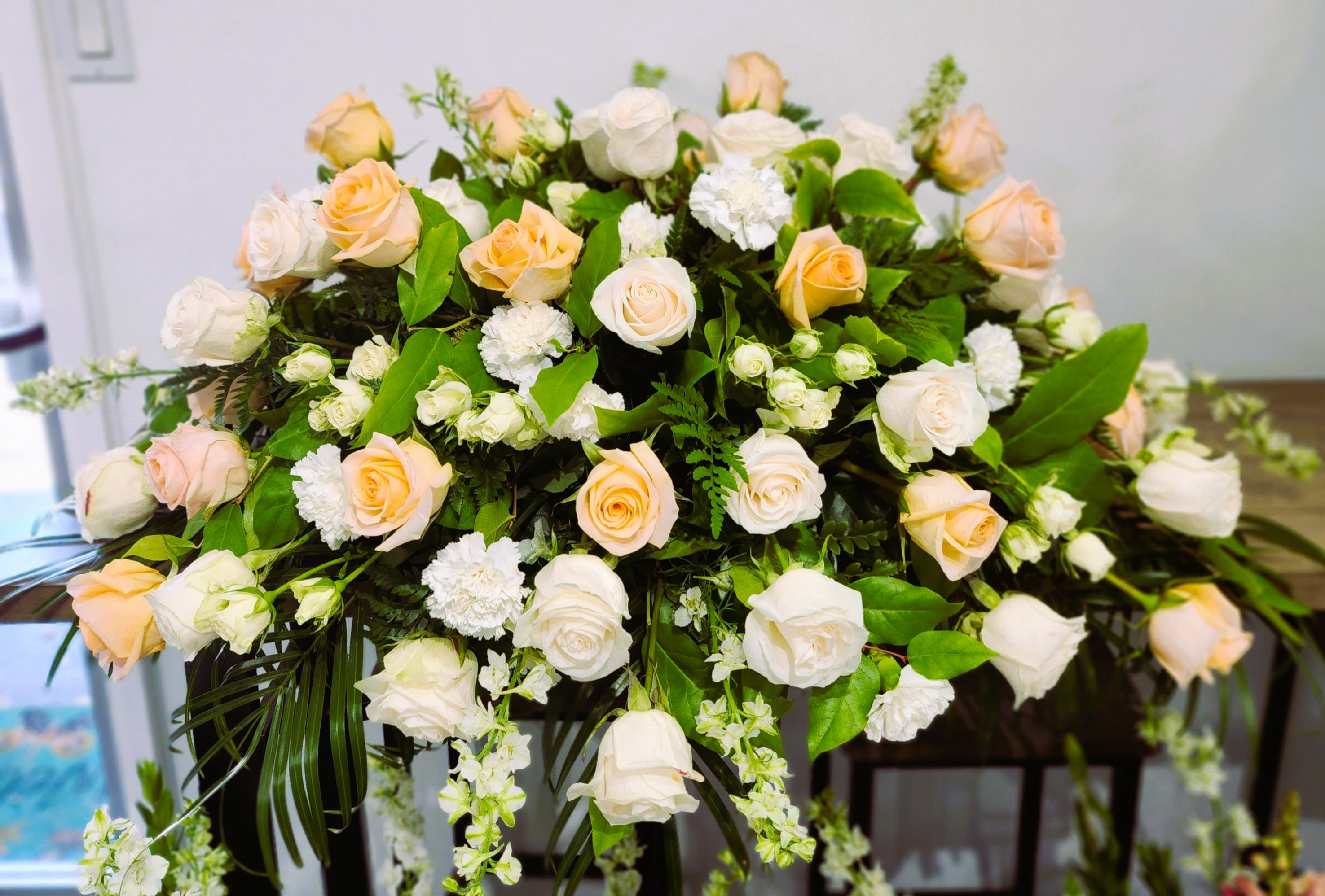 Large arrangement of pale peach and white roses with greenery