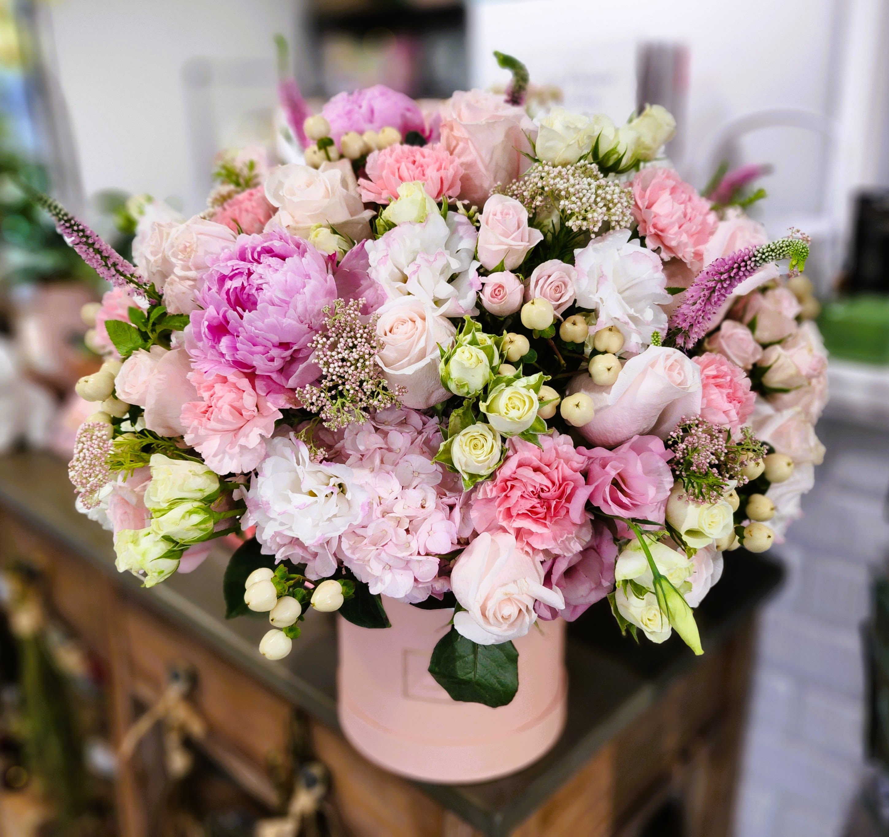 Pink and white mixed flower arrangement in a round box