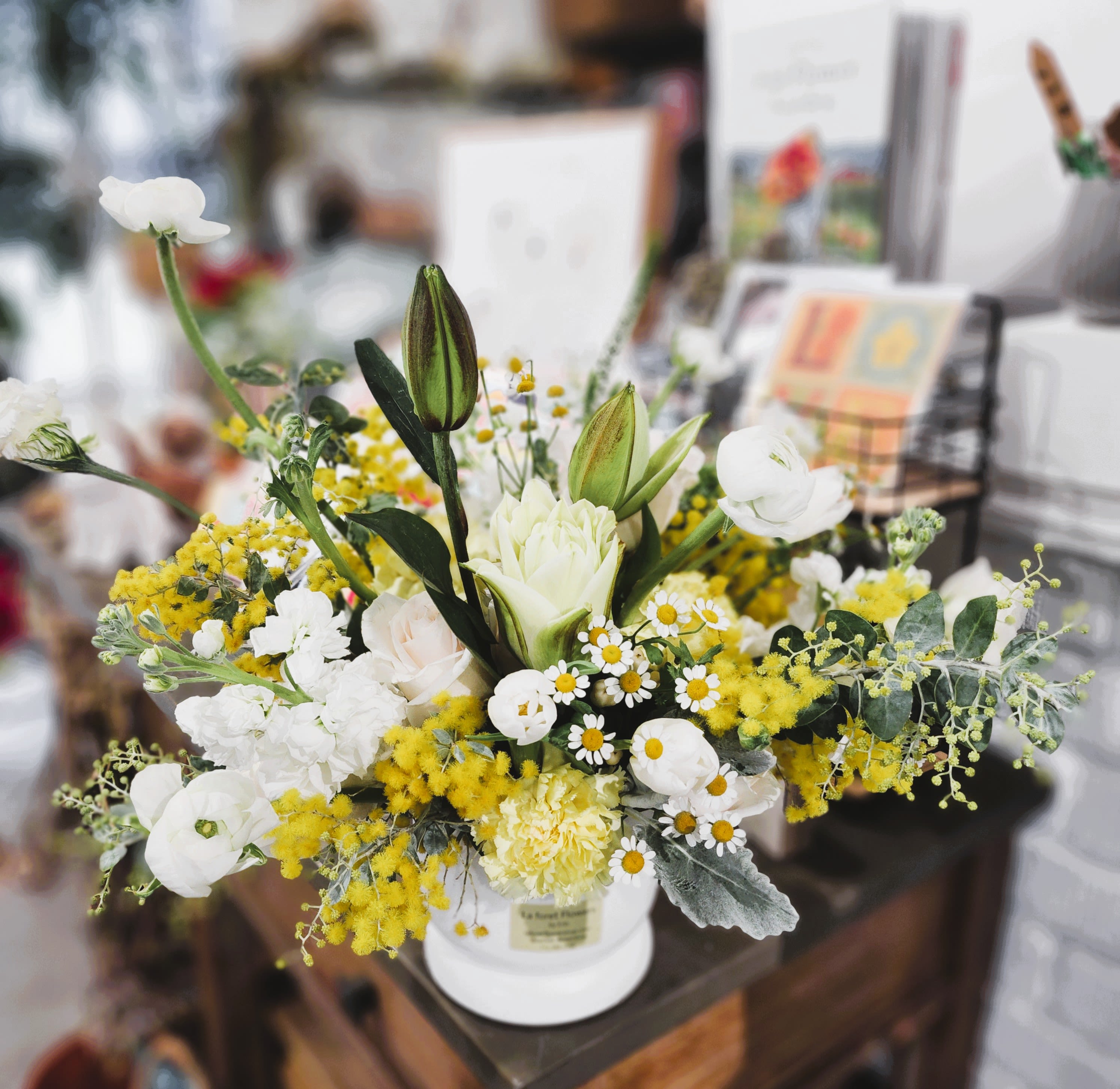 White and yellow floral arrangement in a white vase