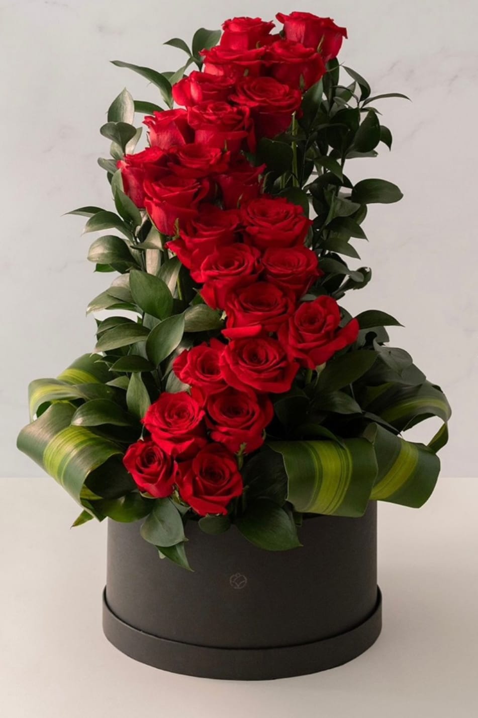 Tall arrangement of red roses in a black hat box
