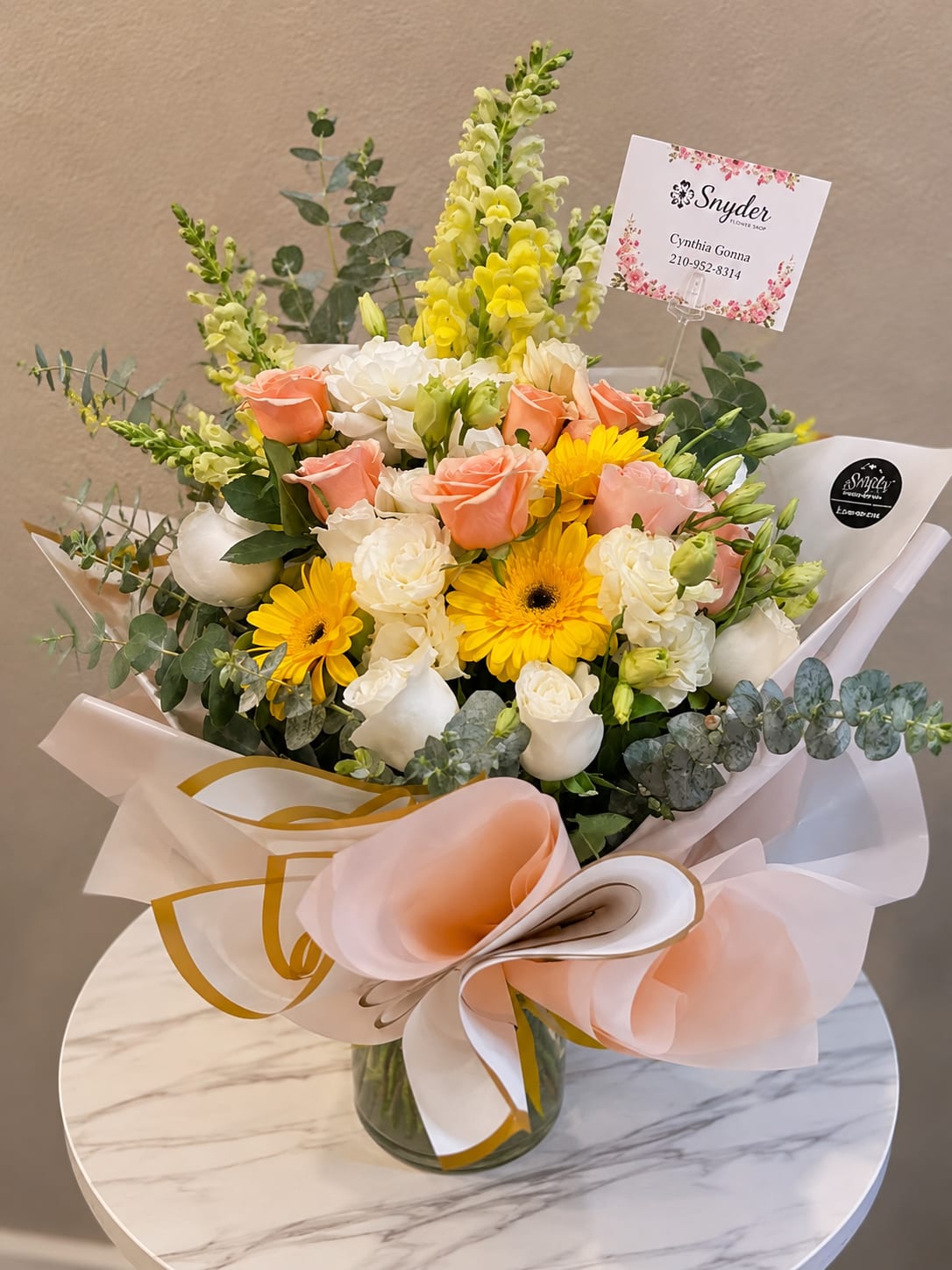 Bouquet of peach and white roses with yellow flowers in a glass vase