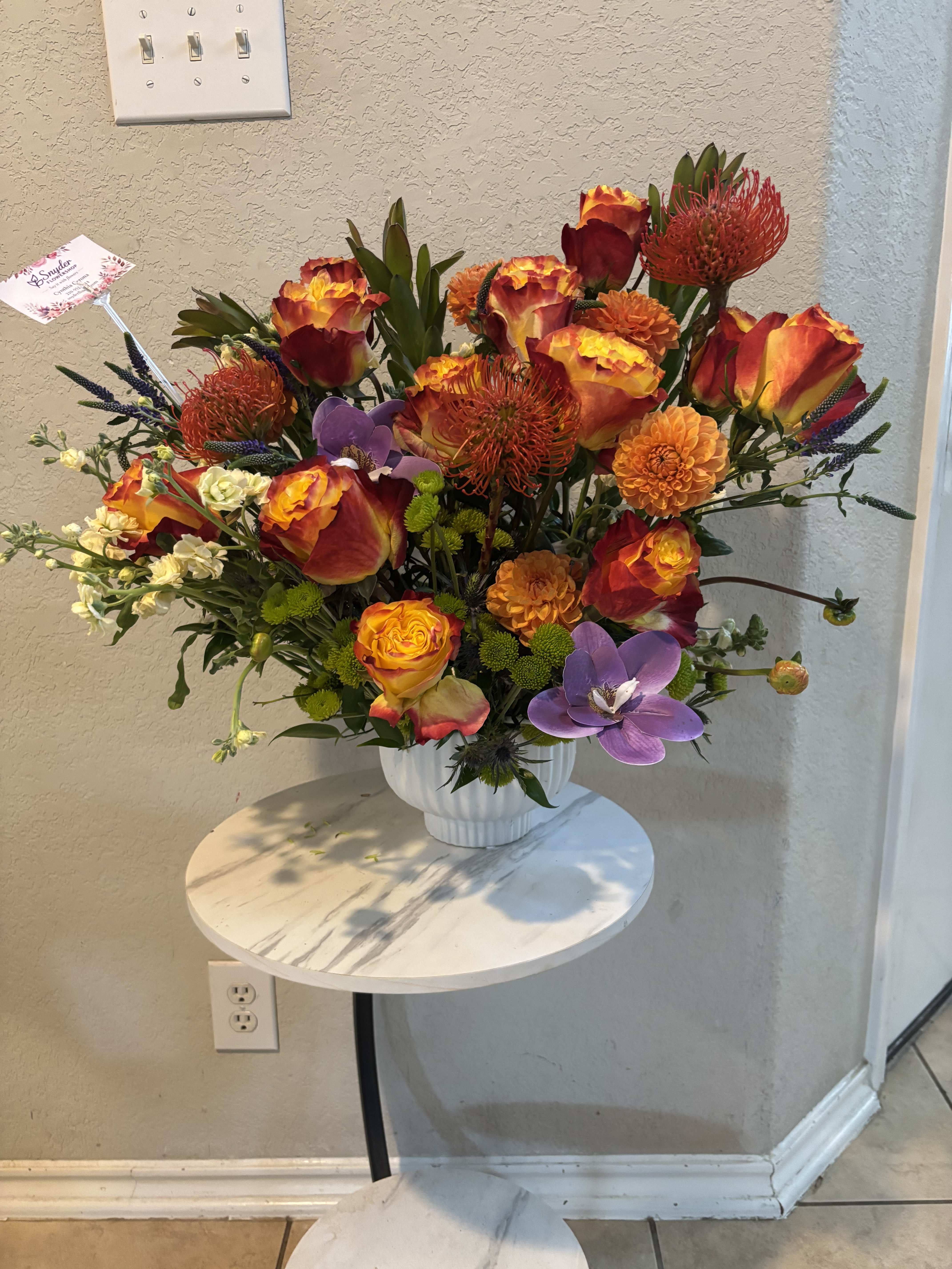 Bright mixed bouquet in a white vase with orange, red, and purple blooms