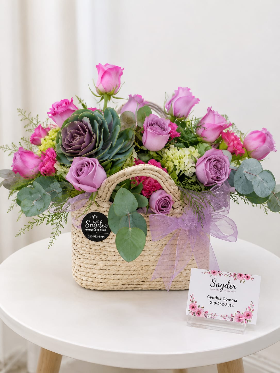 Pink and lavender roses arranged in a woven basket with a ribbon