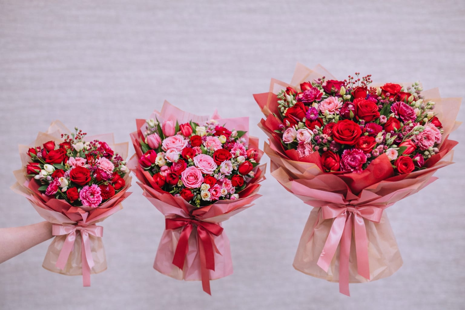 Three bouquets of red and pink roses wrapped in pink paper