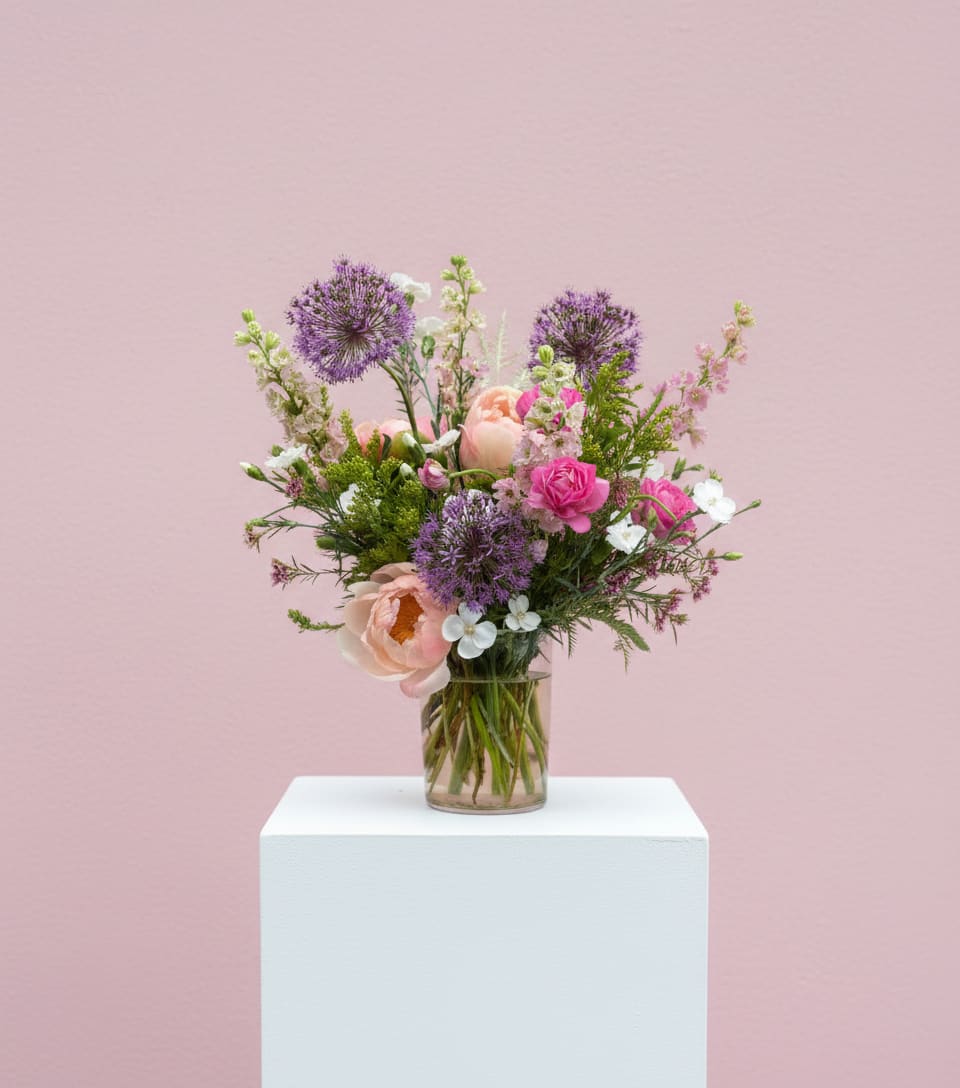 Mixed bouquet of pink and purple flowers in a clear glass vase