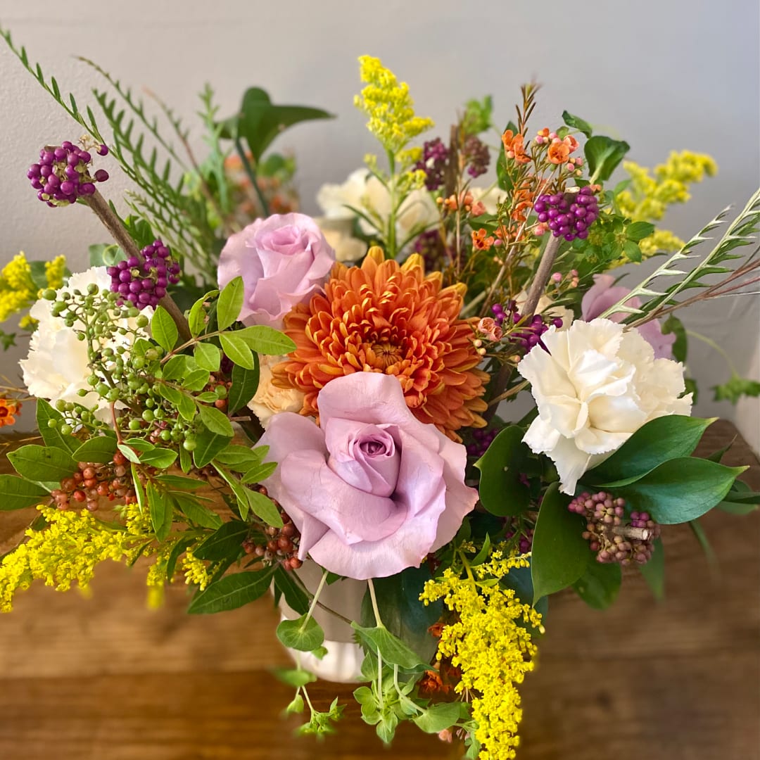 Mixed bouquet with lavender roses, orange chrysanthemum, and white carnations in a vase