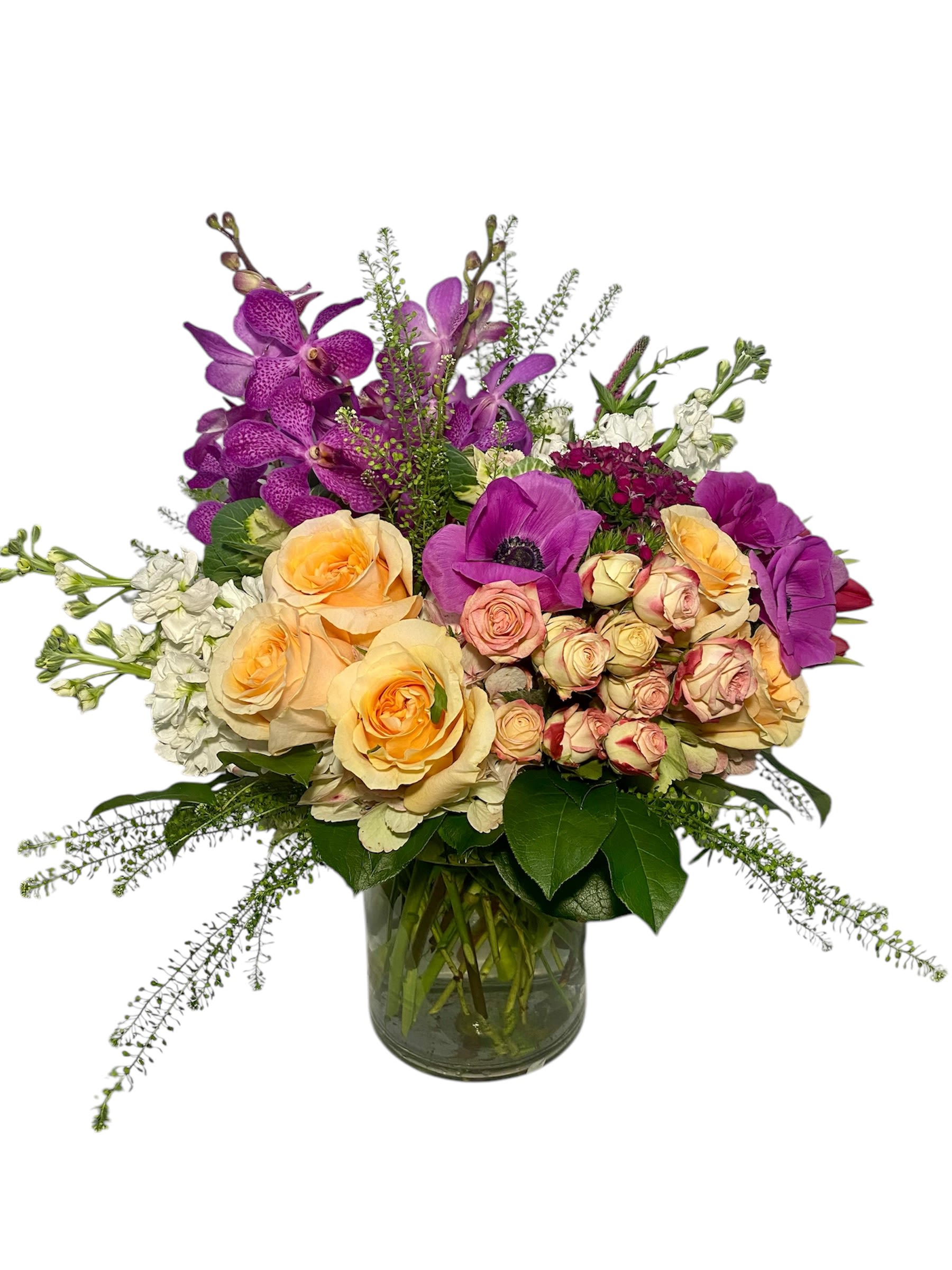 Mixed bouquet of purple orchids and peach roses in a glass vase