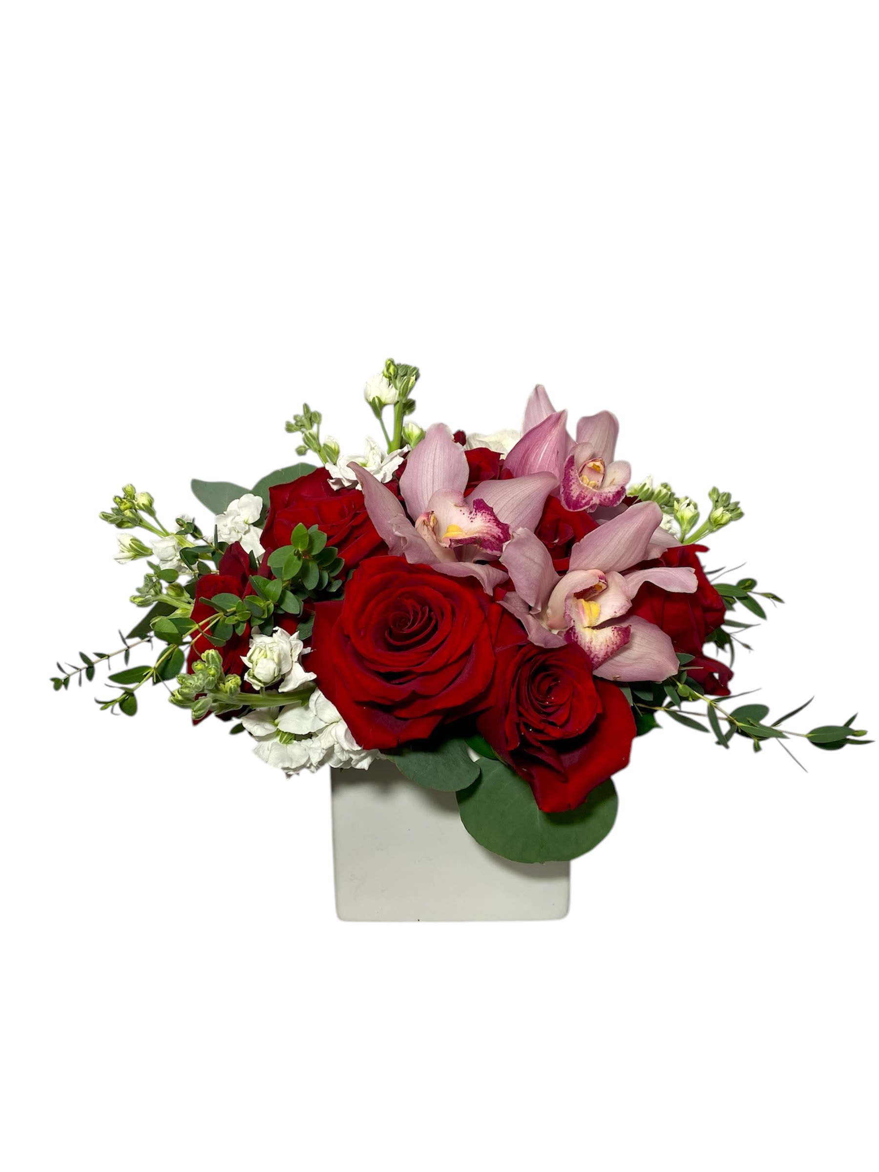 Red roses and pink orchids in a white square vase