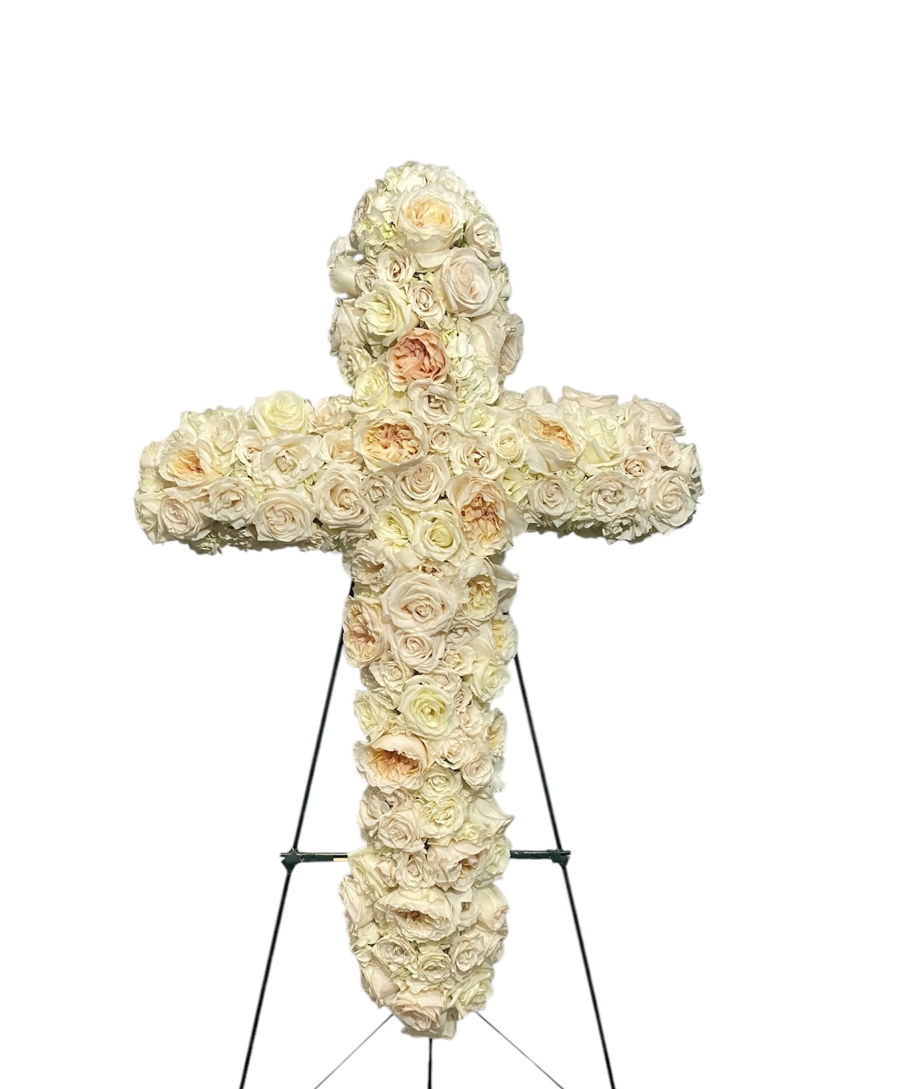 Cross-shaped floral tribute made of cream and blush roses on an easel