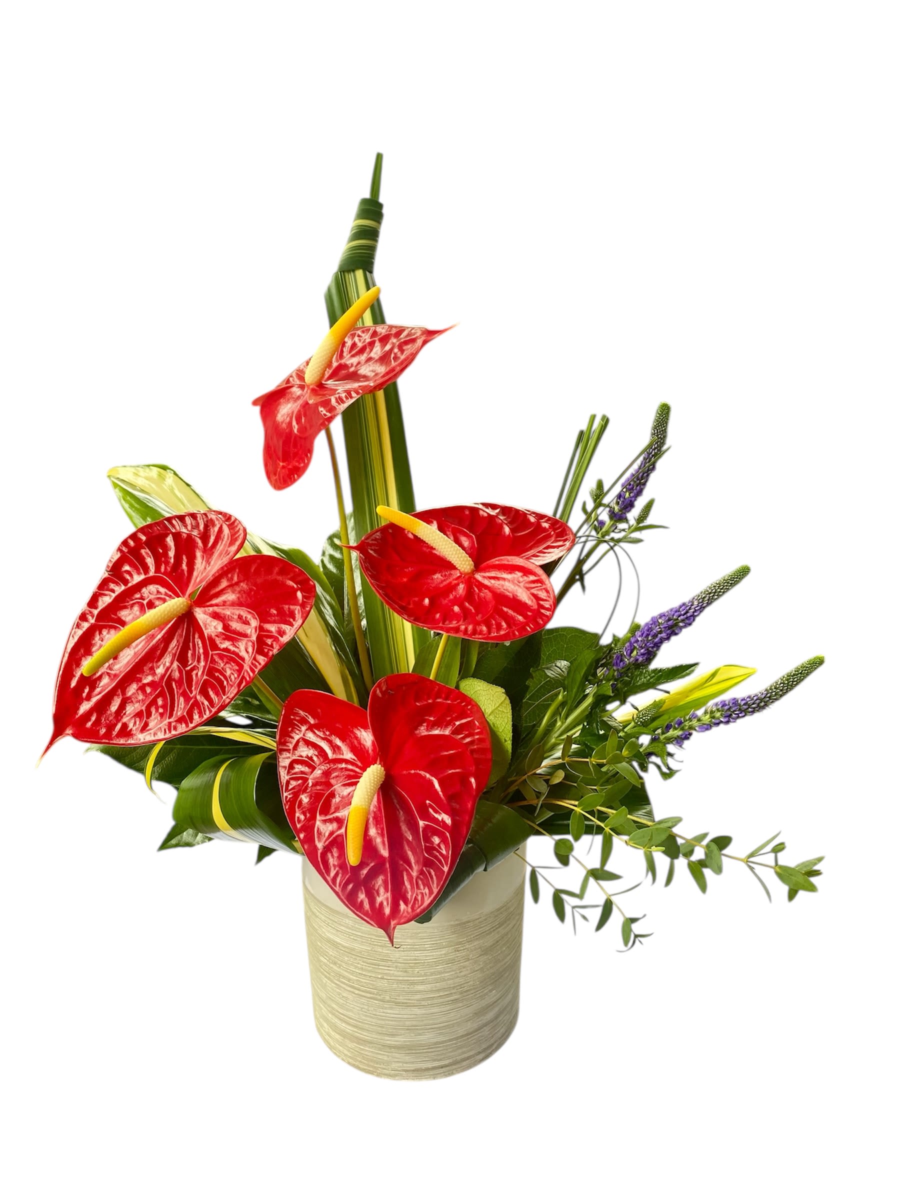 Red anthuriums arranged in a beige vase with purple spikes