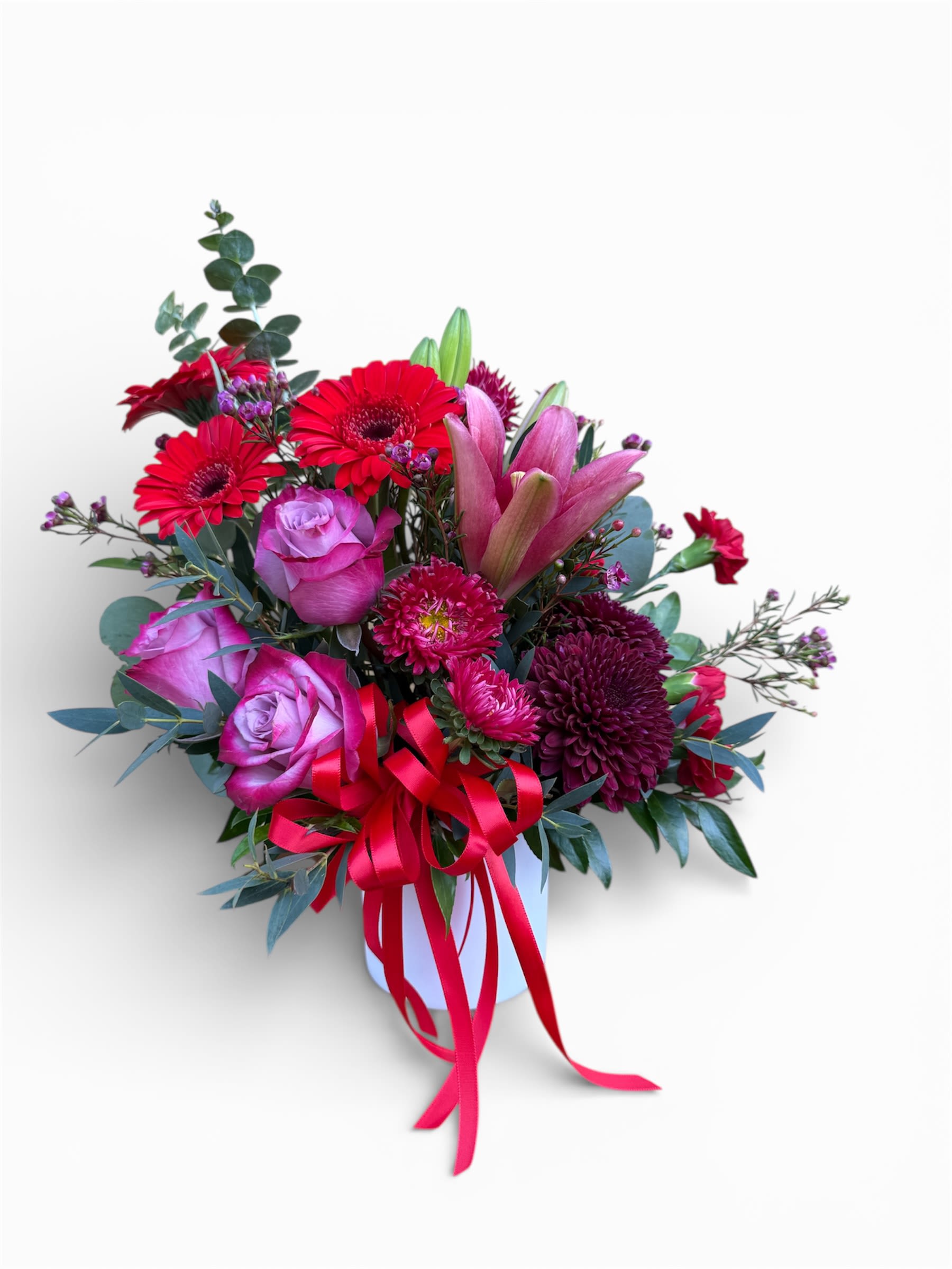 Pink and red mixed bouquet in a white vase with a ribbon