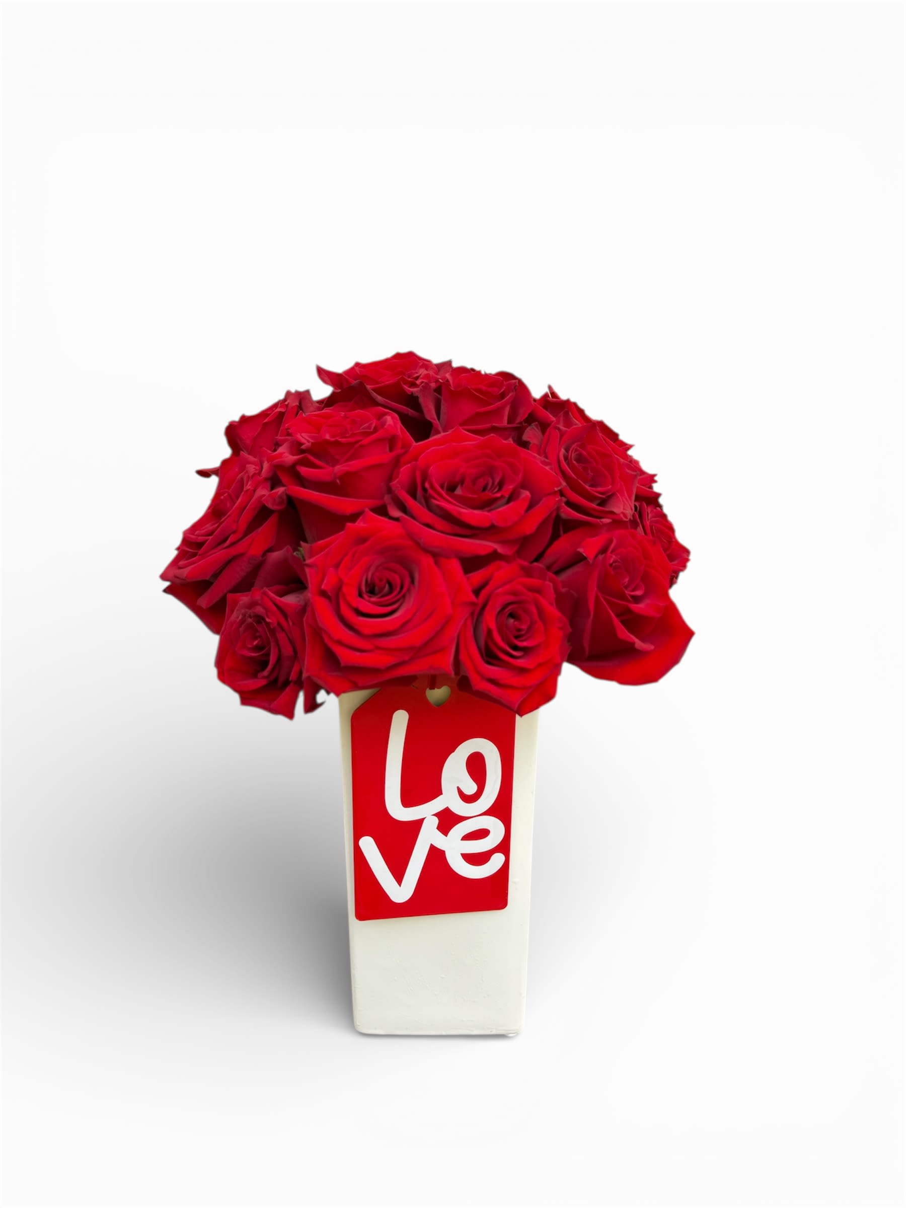 Red roses in a white vase with a red love tag