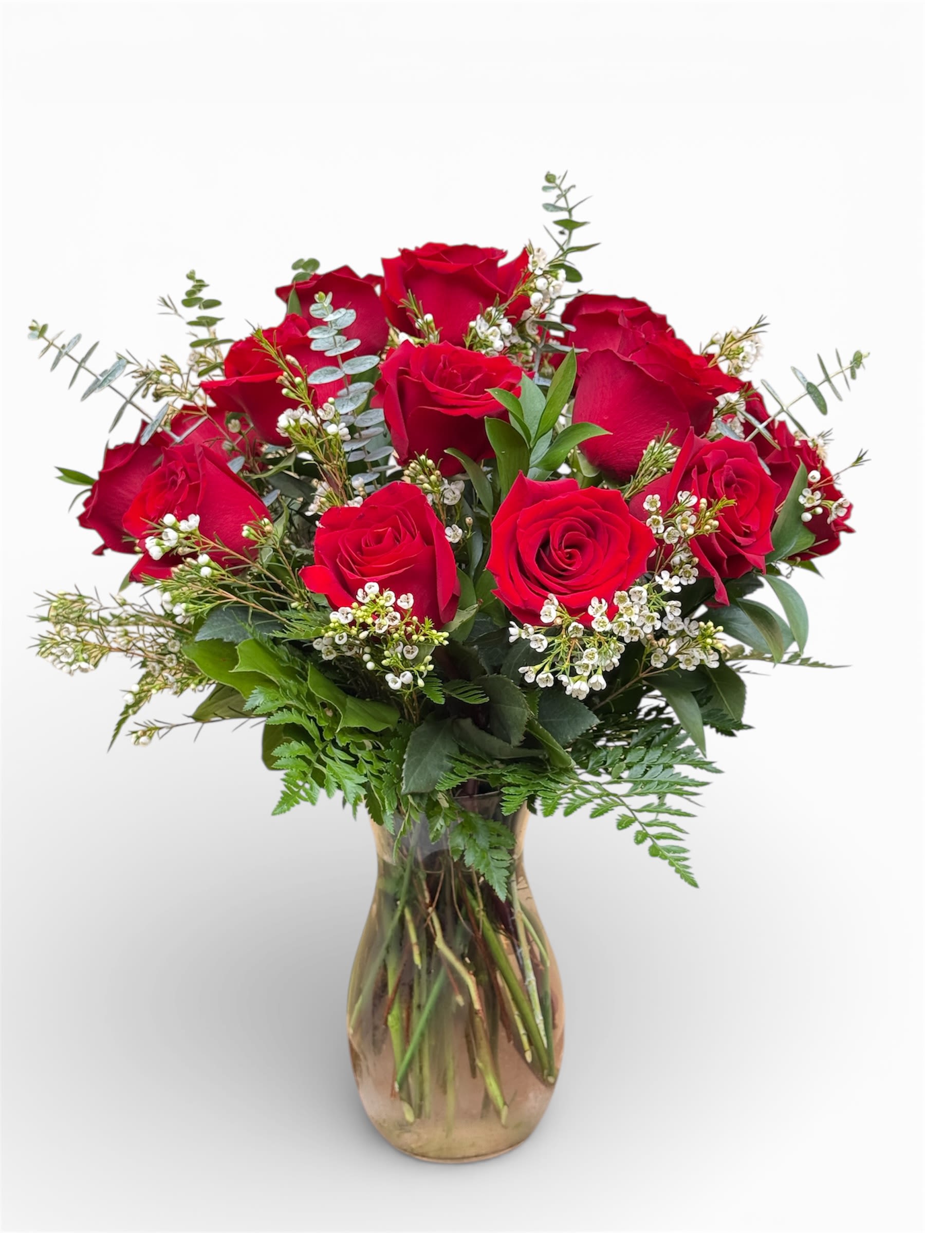 Red roses arranged in a glass vase with small white filler flowers
