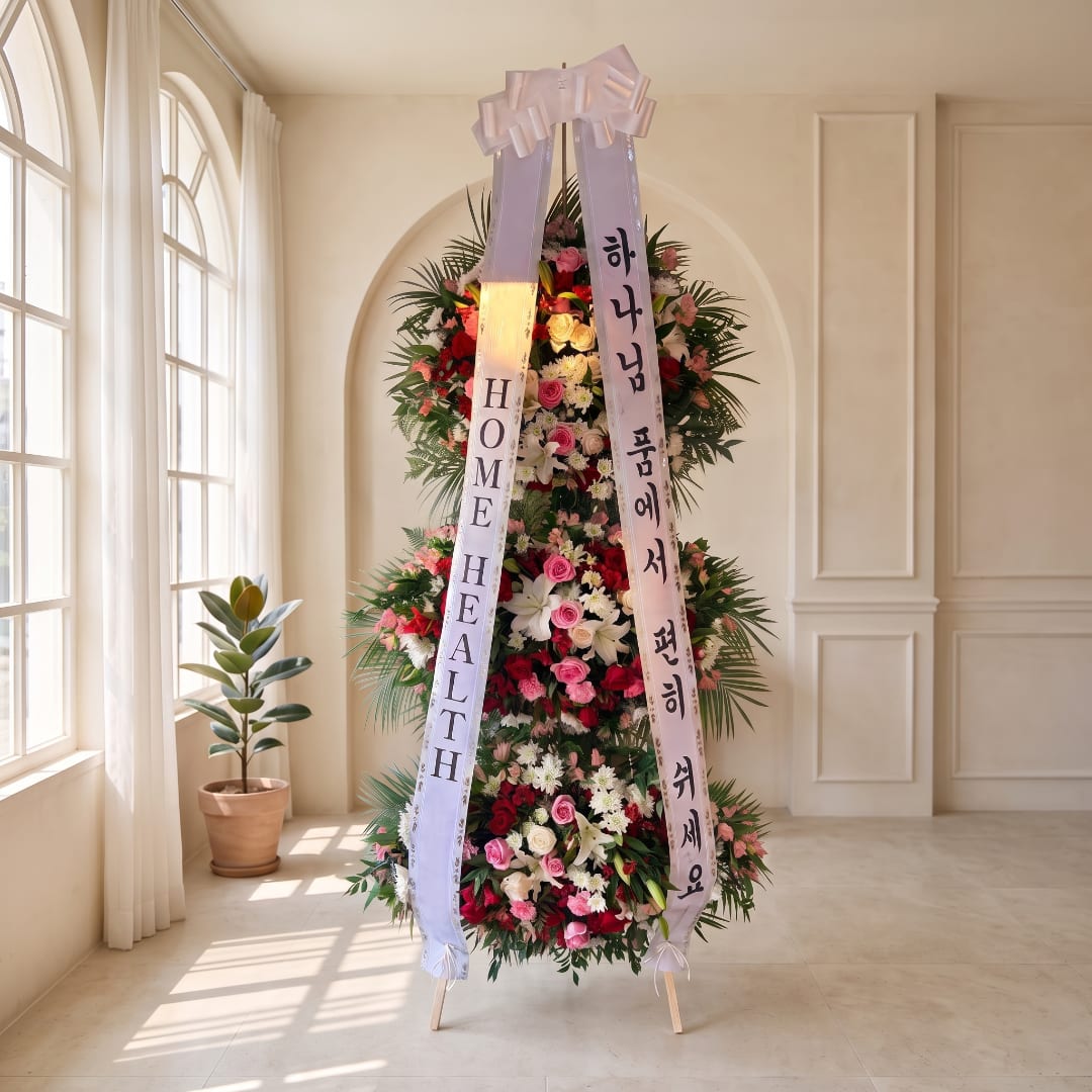 Tall standing floral wreath with pink, white, and red flowers and ribbon banners