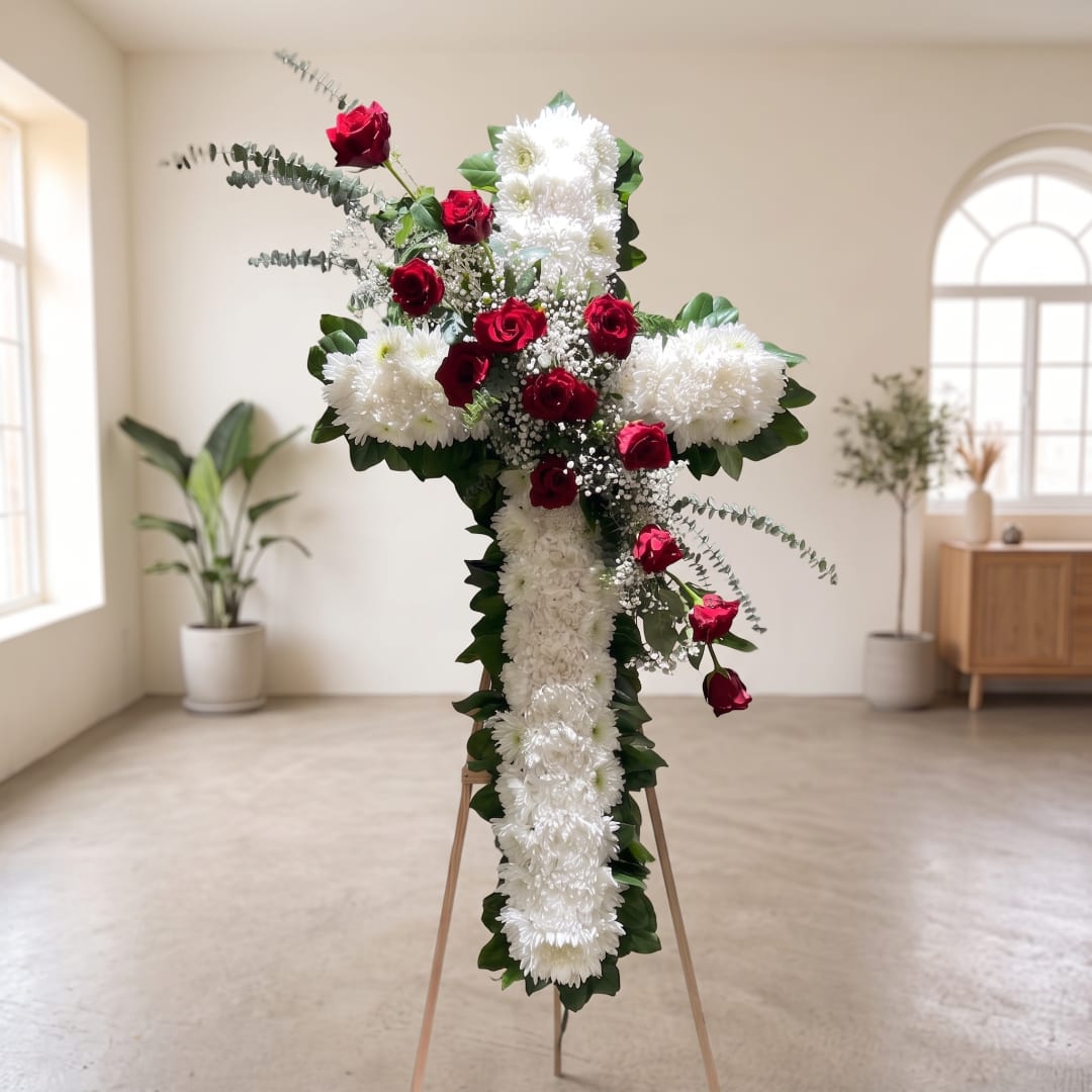 Standing floral cross with white chrysanthemums and red roses on an easel