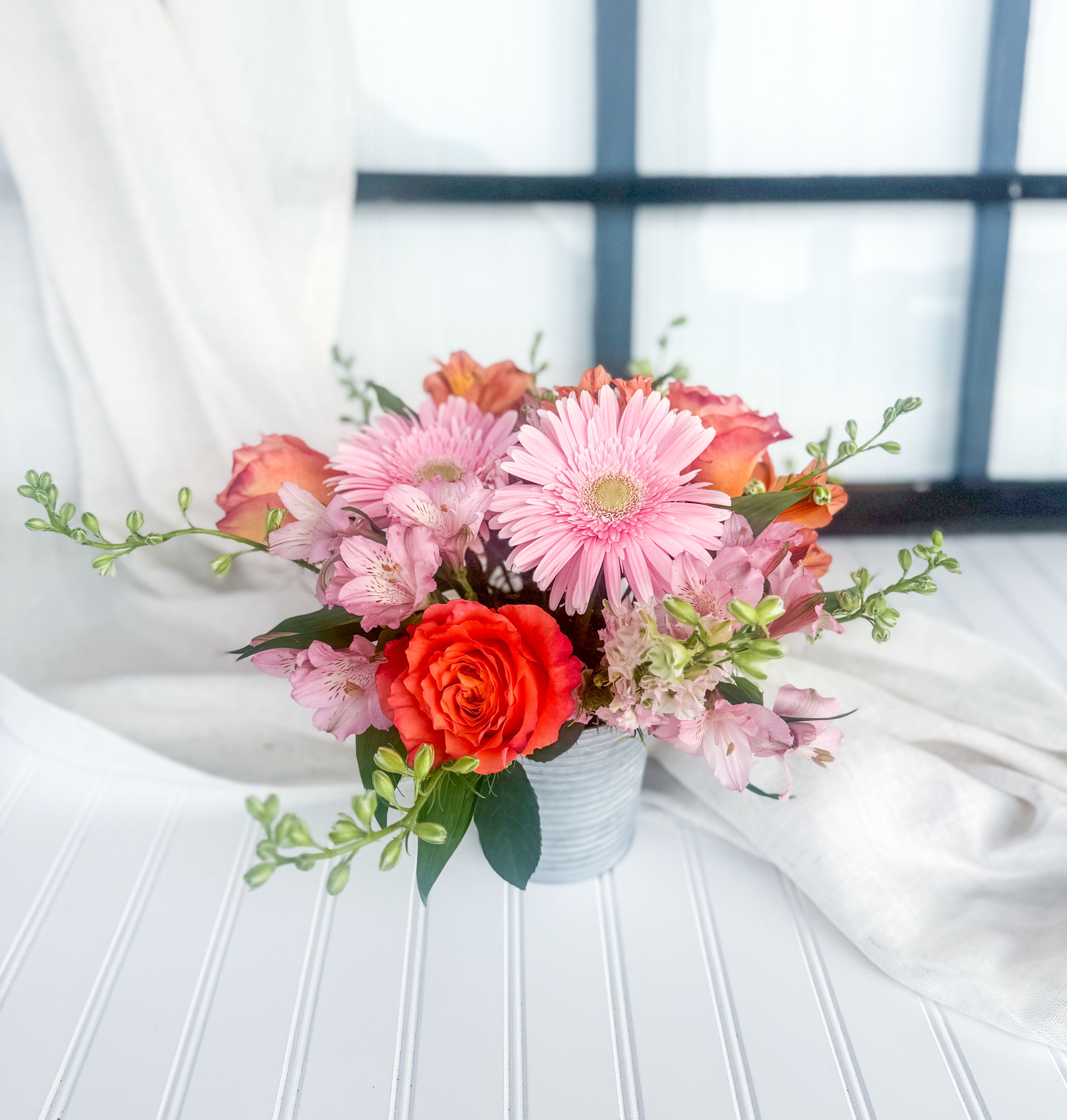 Pink and orange mixed bouquet in a small ribbed vase