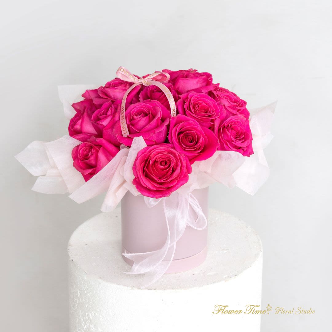 Hot pink roses arranged in a pale pink box with a ribbon bow