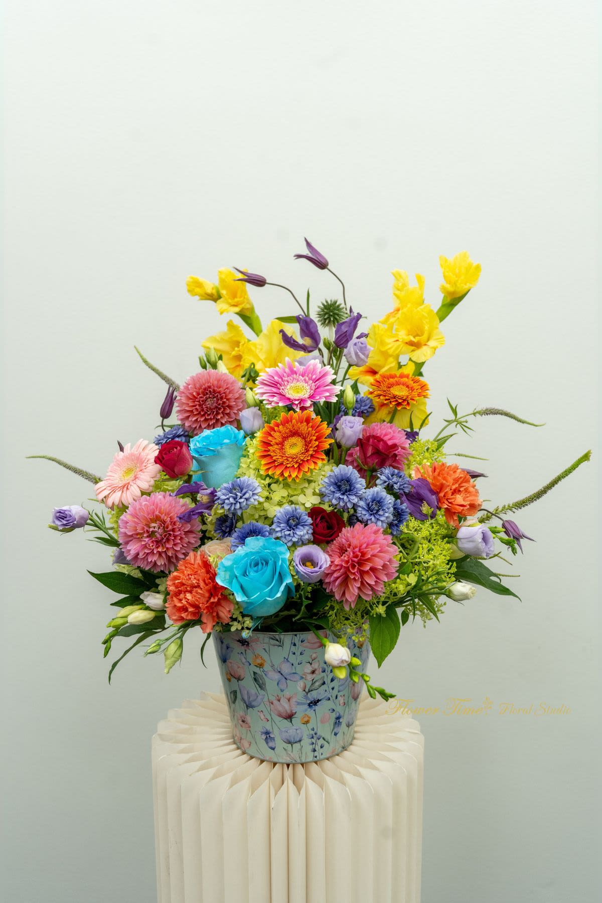 Colorful mixed flower arrangement in a floral tin container