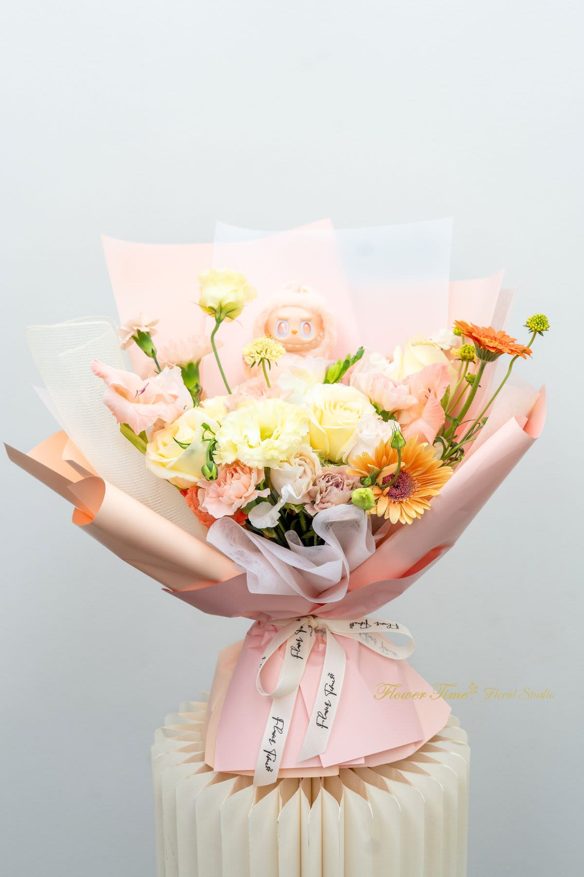 Pastel bouquet of roses, carnations, and gerbera daisies wrapped in pink paper