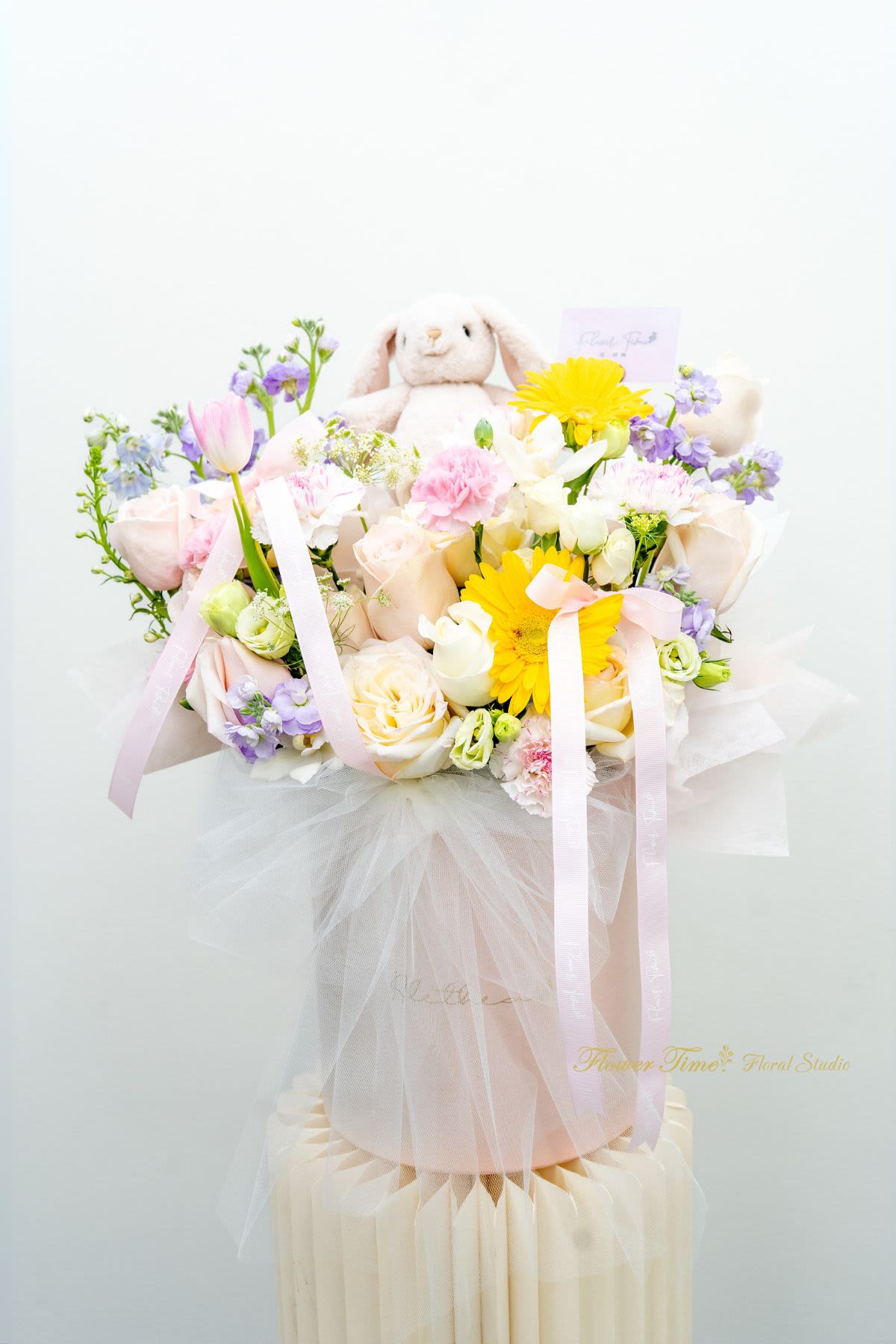 Pastel flower bouquet with a plush bunny and ribbons