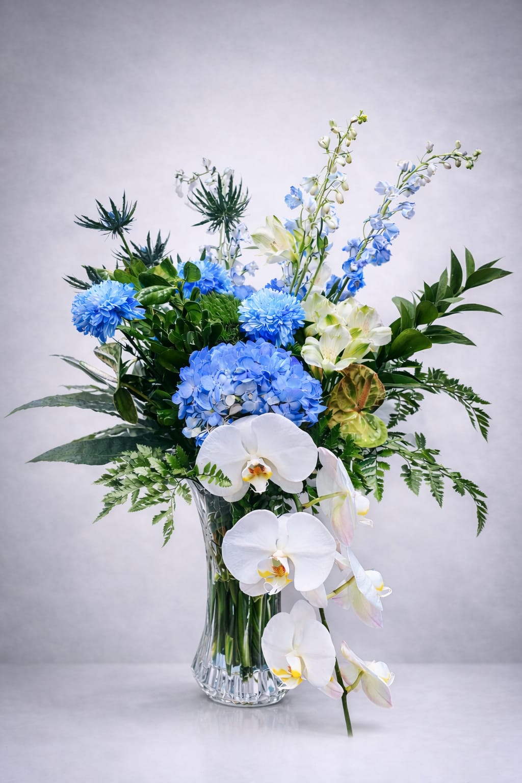 Blue and white floral arrangement in a clear glass vase