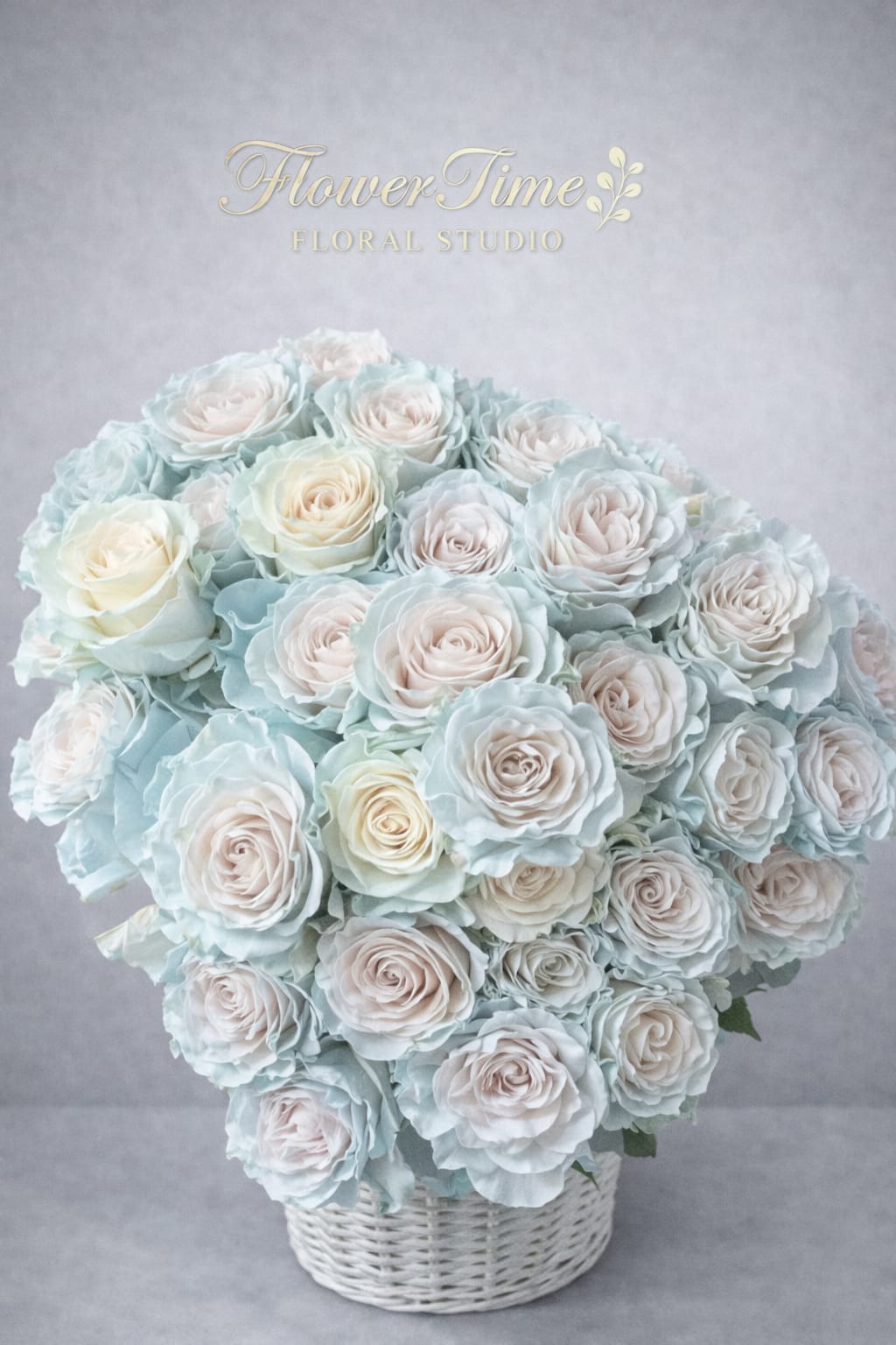 Large bouquet of pale blue and blush roses in a white basket