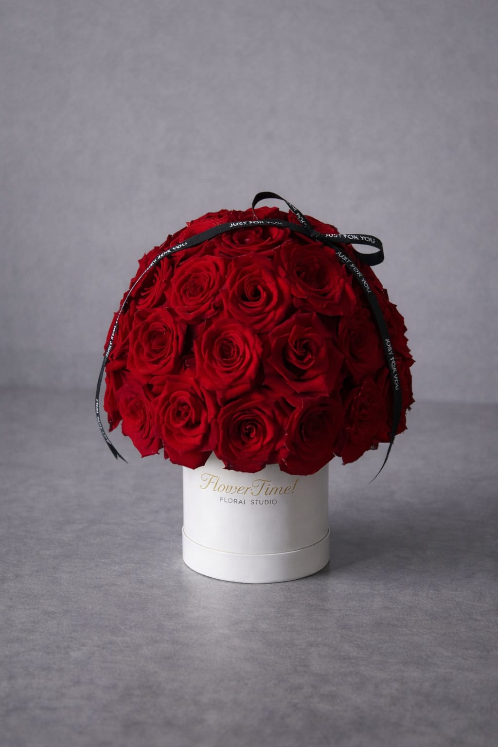 Red rose arrangement in a white hat box with a black ribbon