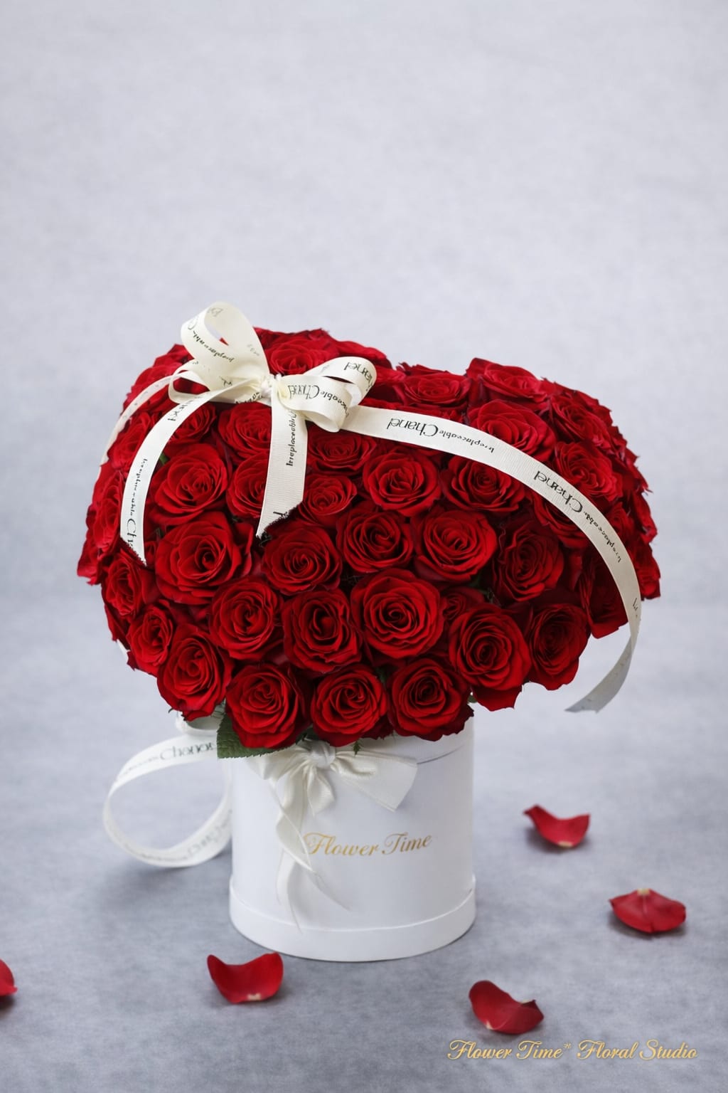 Large bouquet of red roses in a white hatbox with ribbon