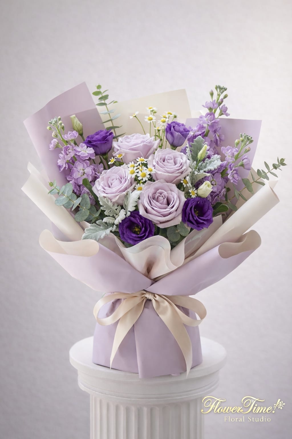 Lavender and purple bouquet of roses and small filler flowers wrapped in pastel paper