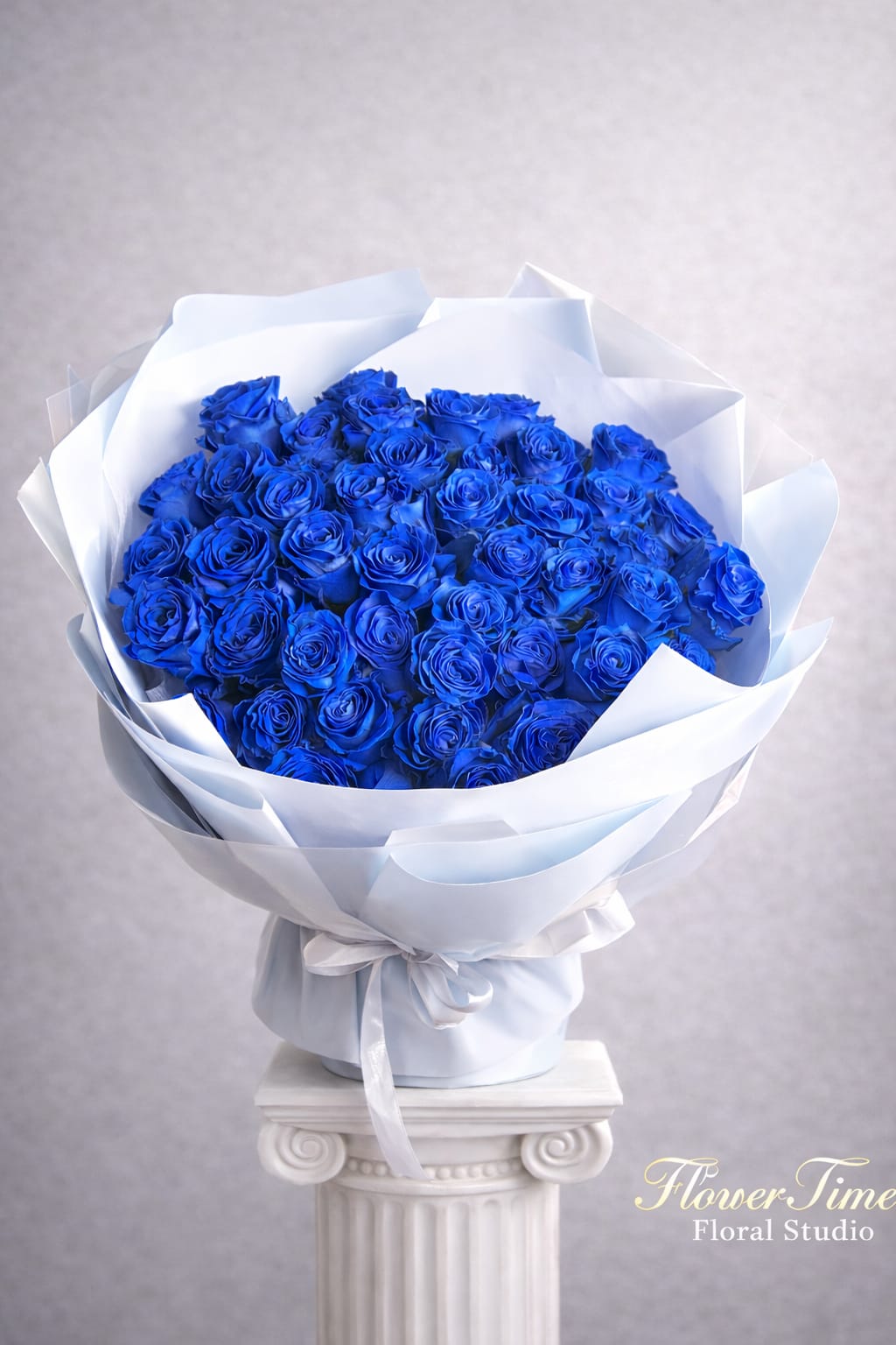 Bouquet of vivid blue roses wrapped in white paper