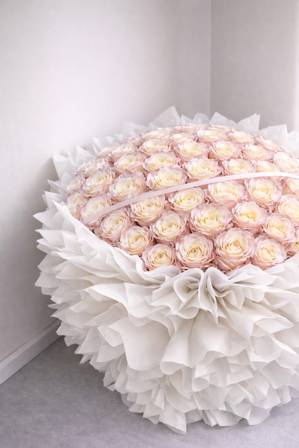 Large bouquet of pale pink and cream roses wrapped in white paper