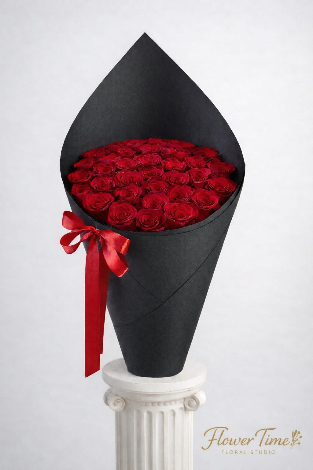 Red roses arranged in a black cone wrap with a red ribbon