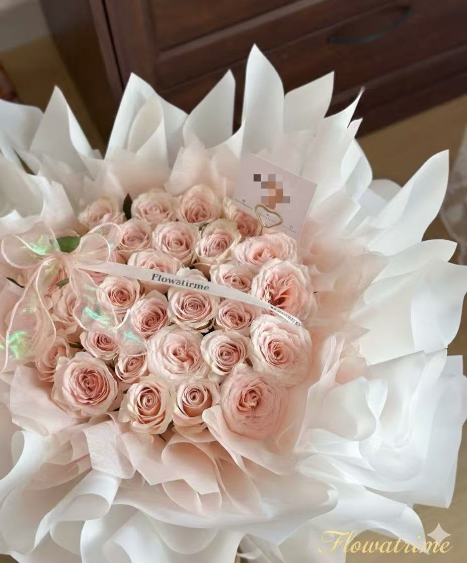 Bouquet of pale pink roses wrapped in white paper