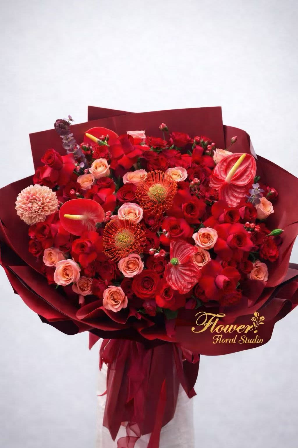 Bouquet of red and blush flowers wrapped in burgundy paper