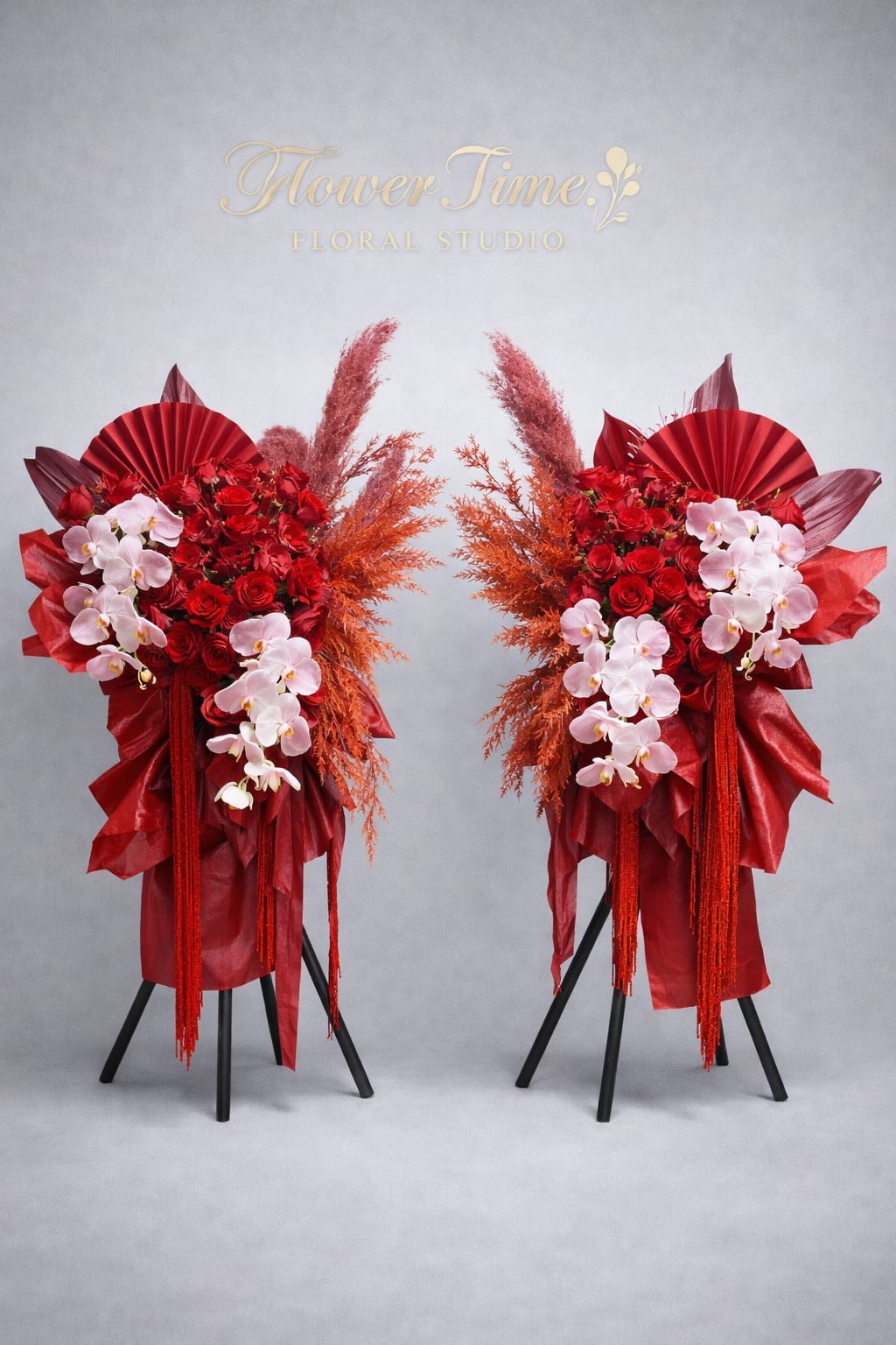 Two red floral standing arrangements with pink orchids on black stands