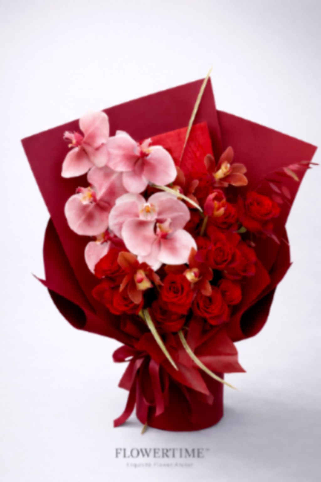 Bouquet of pink orchids and red roses wrapped in red paper