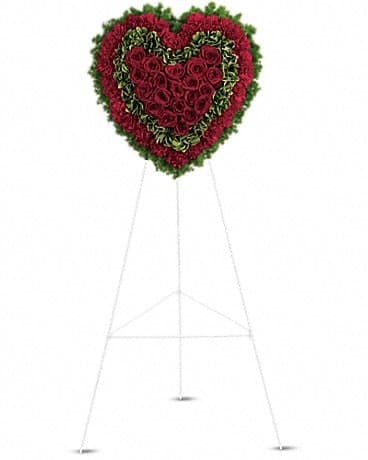 Heart-shaped standing floral tribute with red roses and greenery on an easel