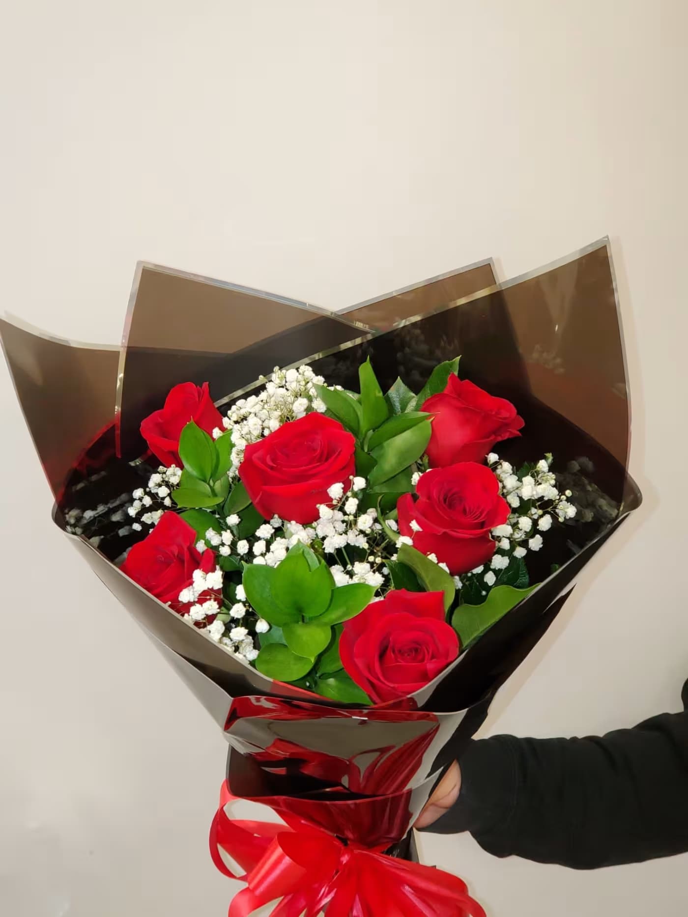 Bouquet of red roses with baby's breath in black wrap and red ribbon