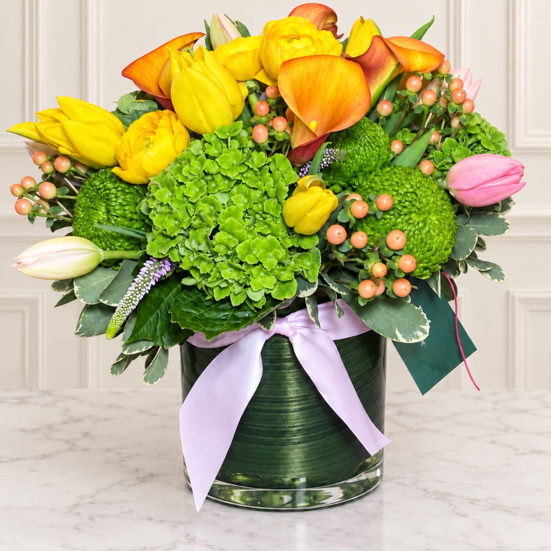 Bright bouquet of yellow and orange tulips with green blooms in a glass vase