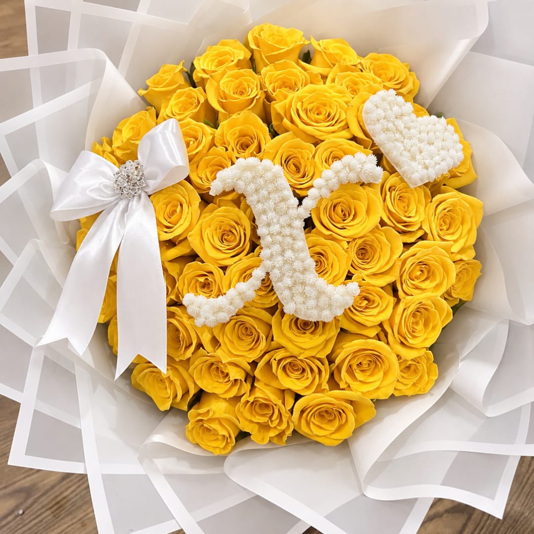 Bouquet of yellow roses with white floral heart accents and a white ribbon