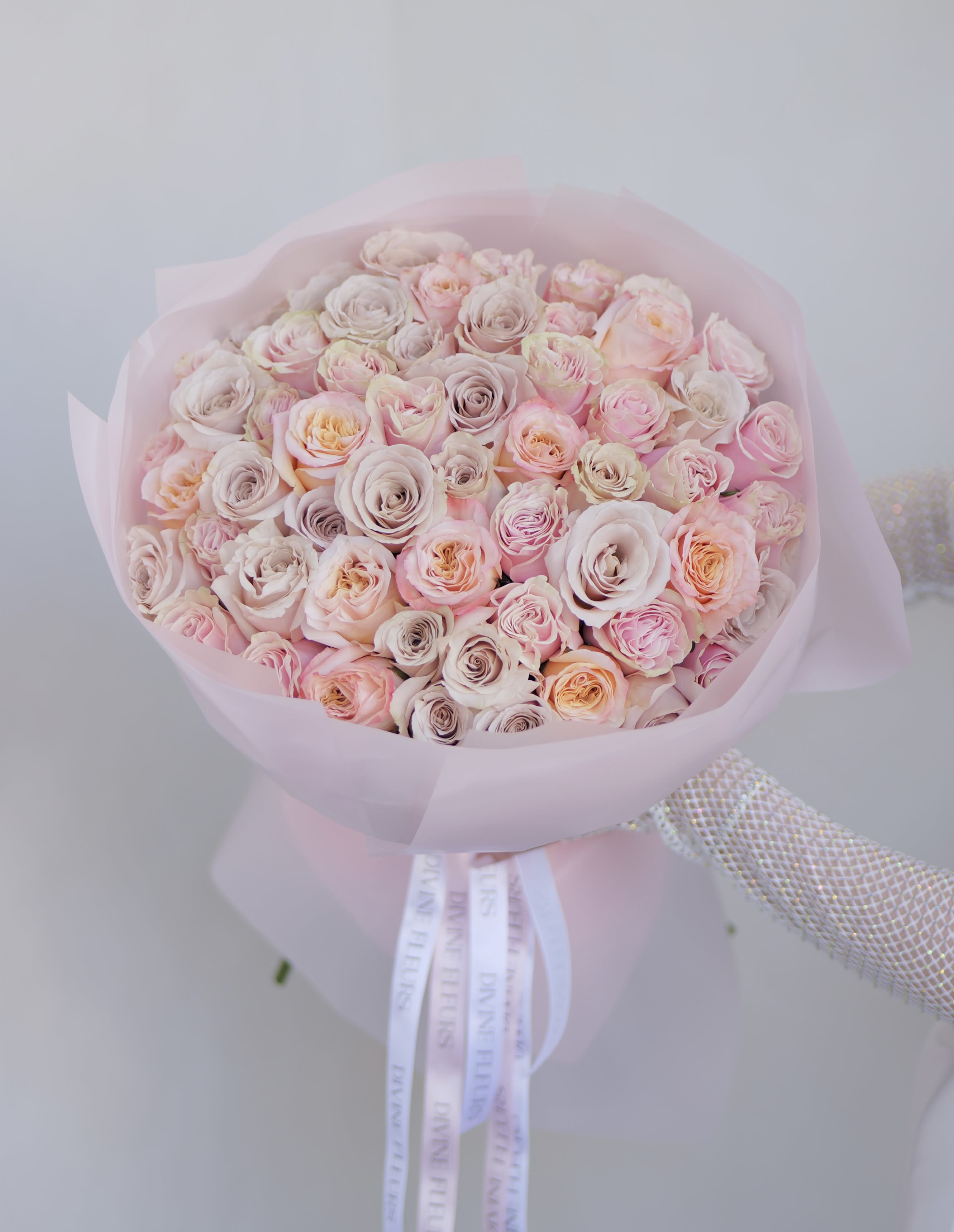 Bouquet of pale pink and cream roses wrapped in pink paper