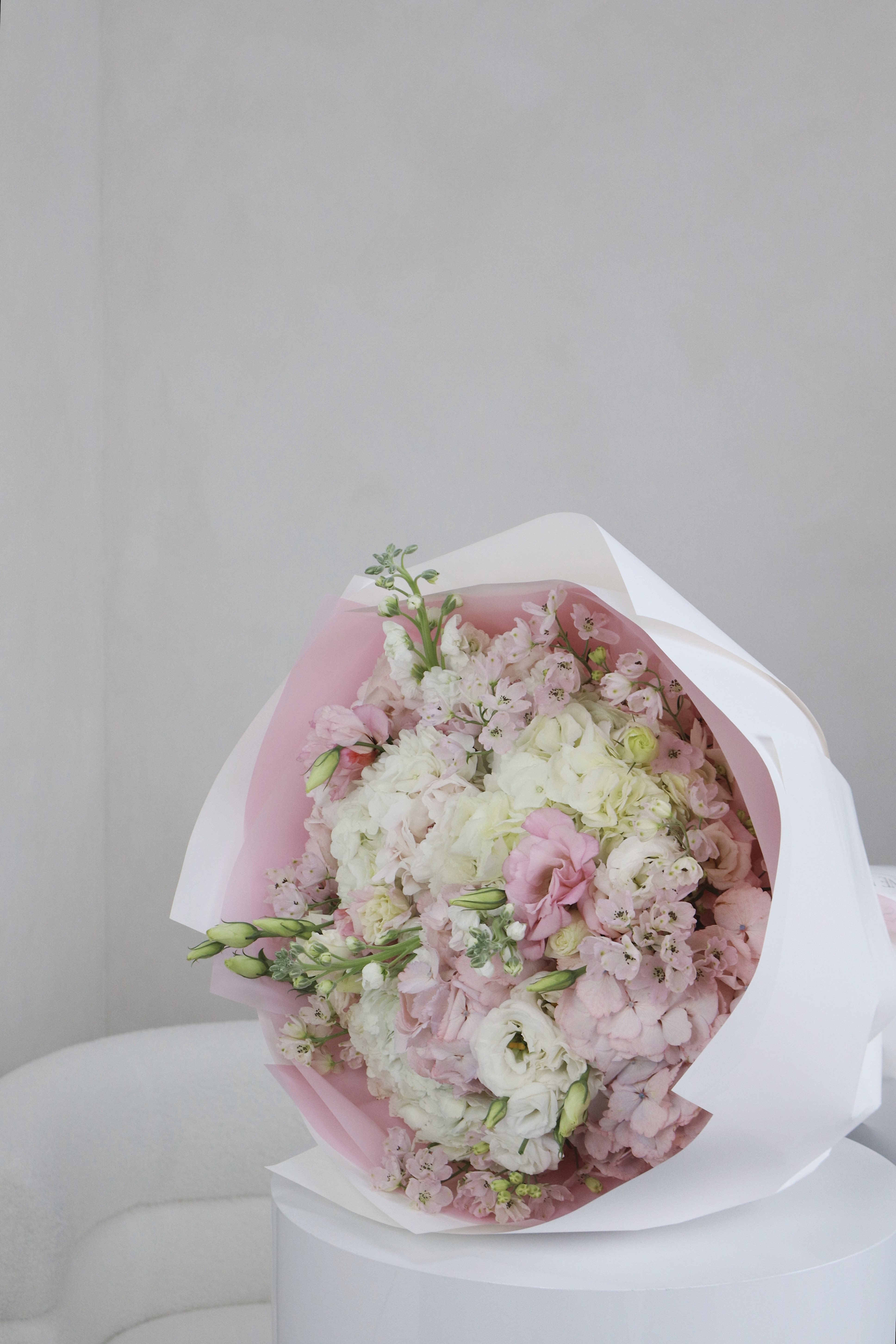 Bouquet of pale pink and white flowers wrapped in pink and white paper