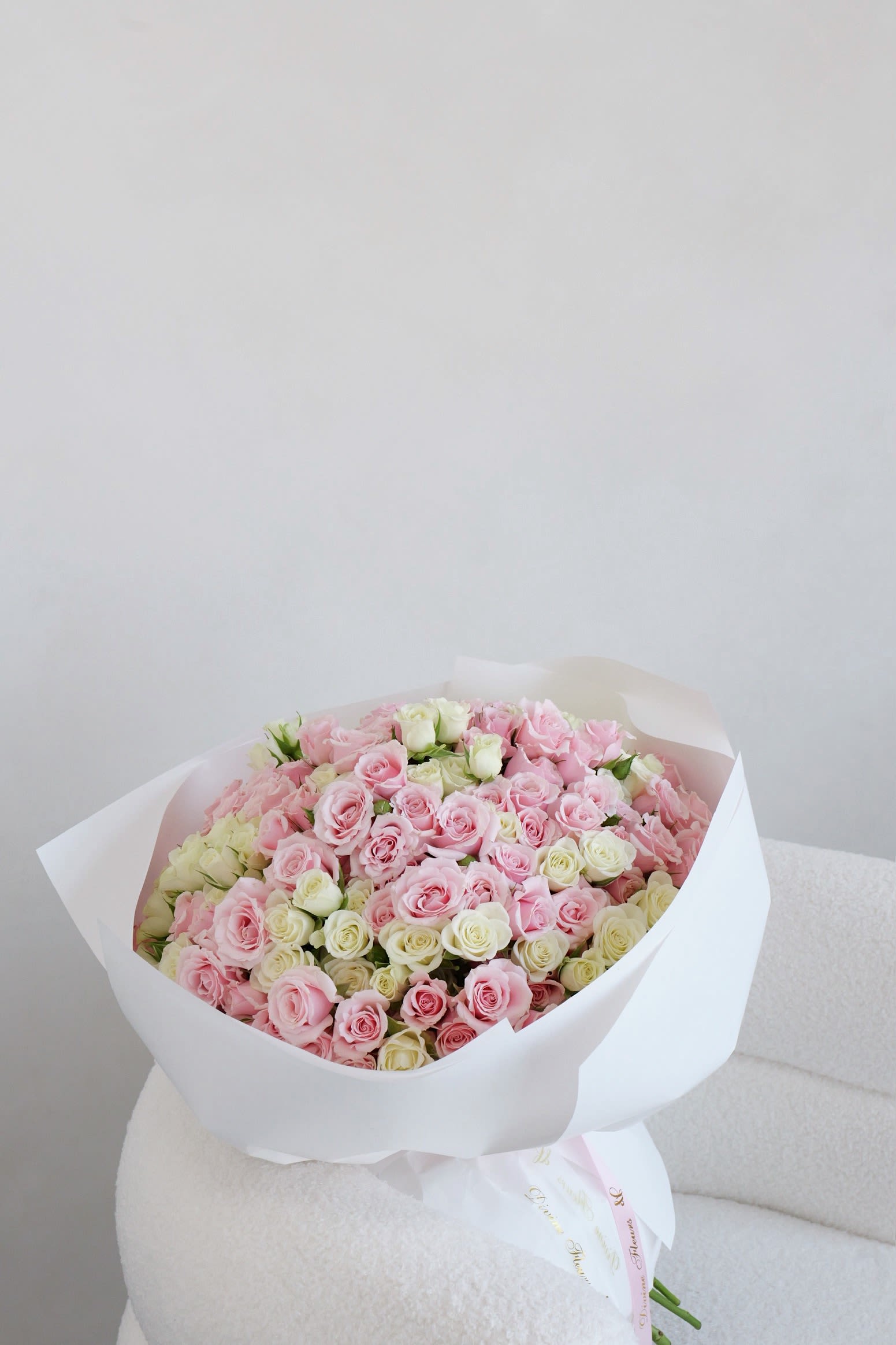 Large bouquet of pink and white roses wrapped in white paper