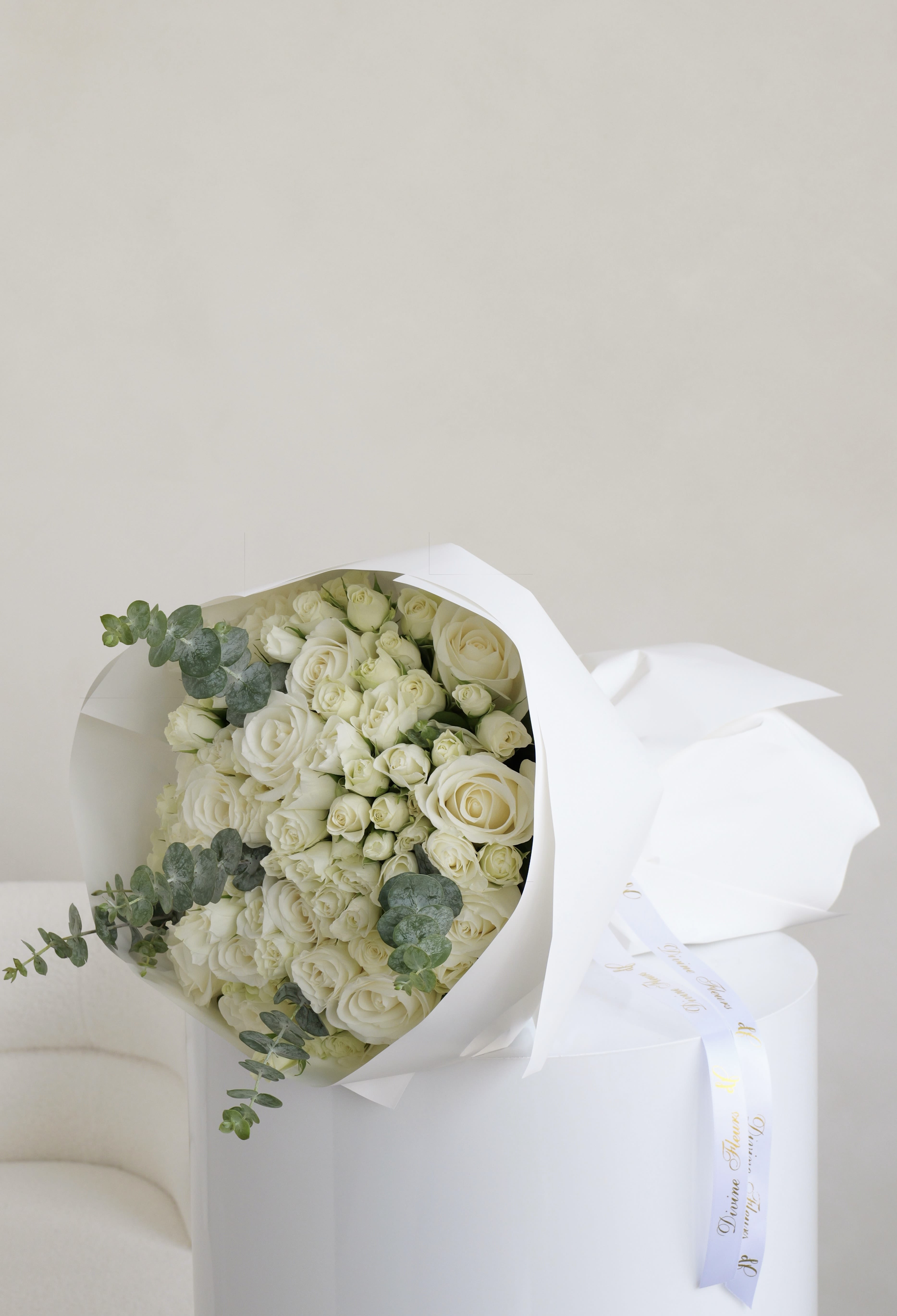 Bouquet of white roses wrapped in white paper with eucalyptus